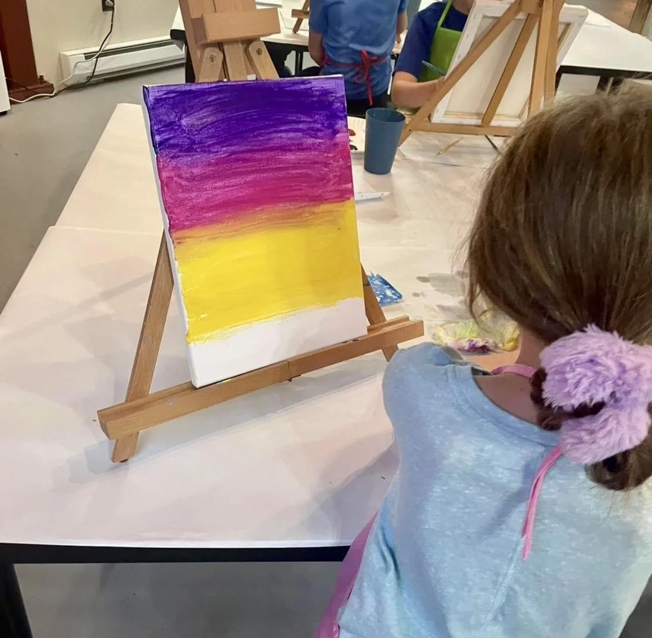 Child painting a colorful canvas during a kids paint day at Inspiration Haven Art Studio in Heber City, Utah.