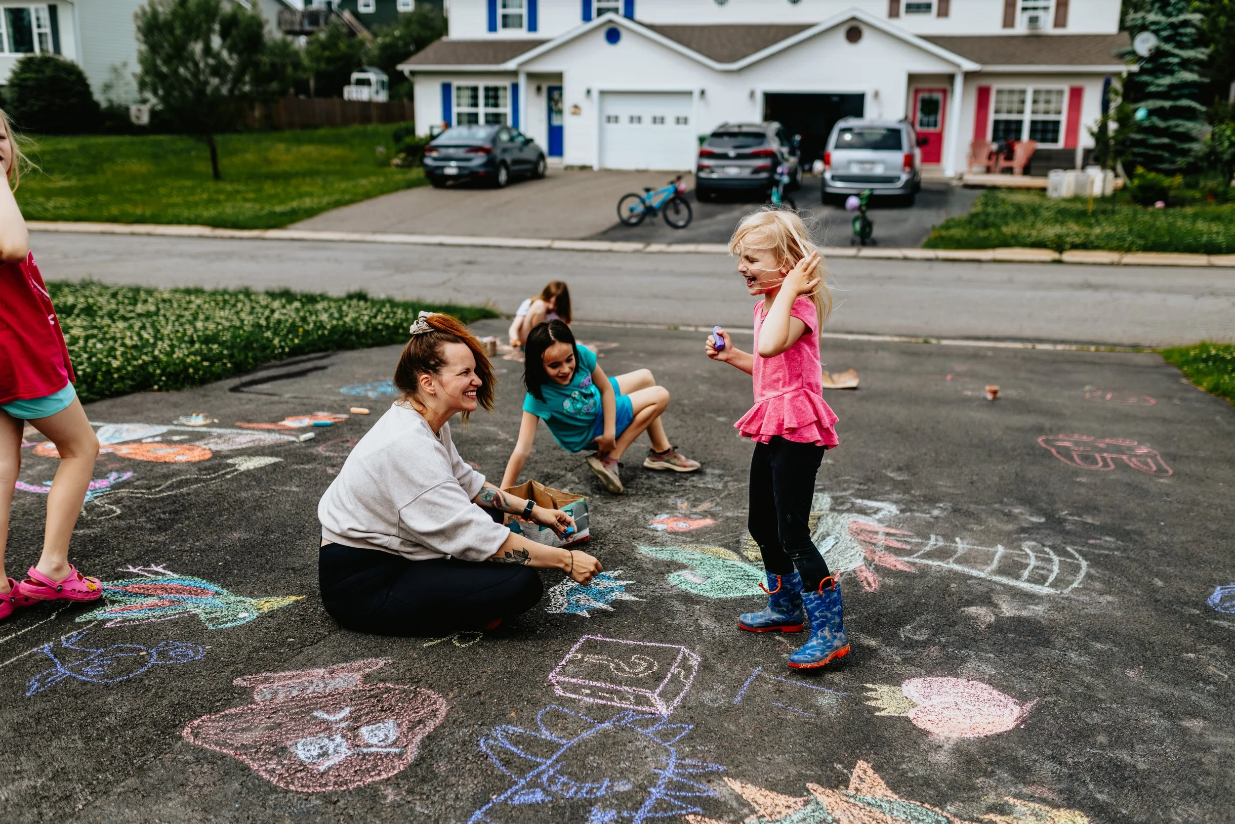 Natural family photos Fredericton Oromocto New Brunswick, mom and kids drawing with chalk in backyard lifestyle session.