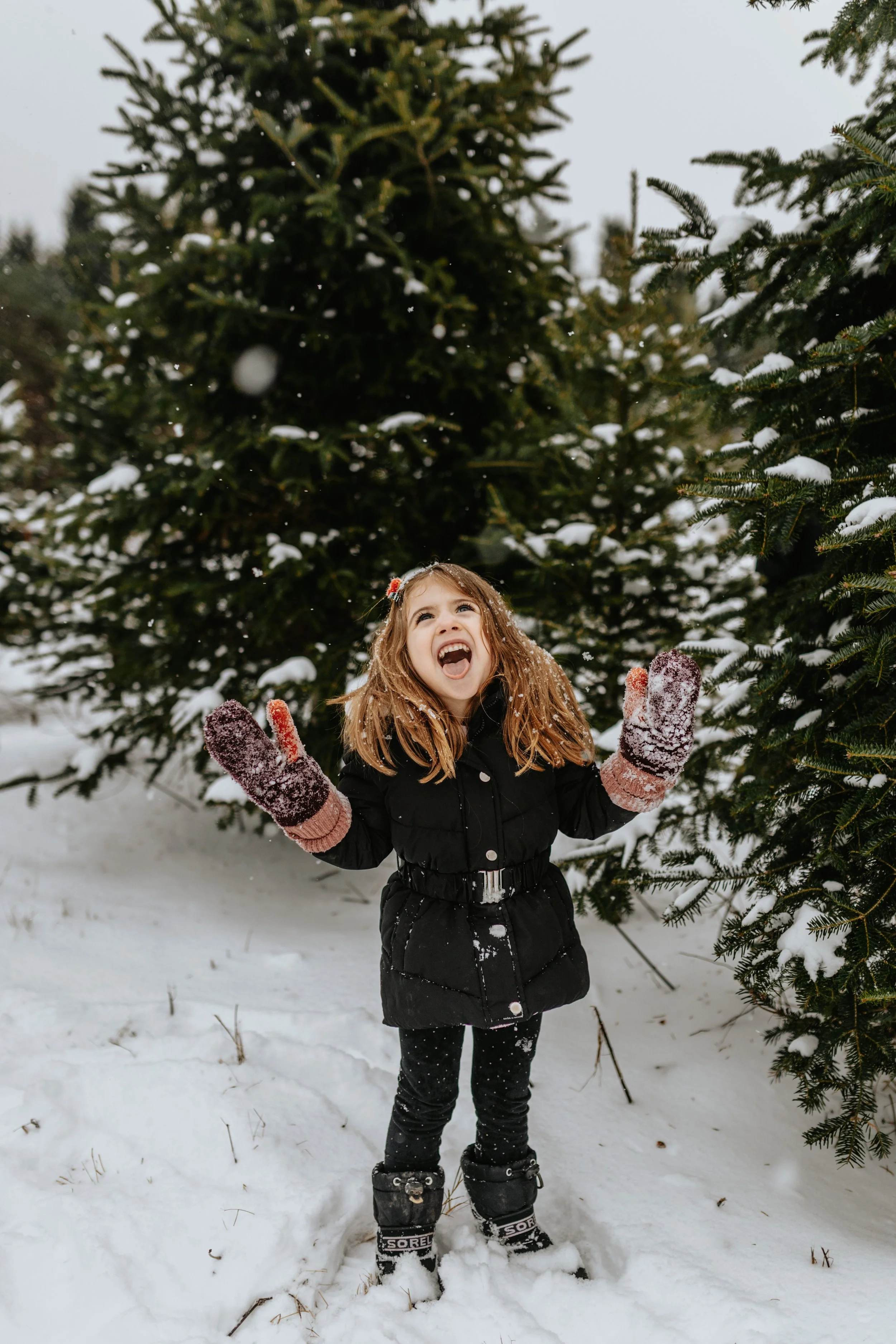 A little girl catches snowflakes on her tongue
