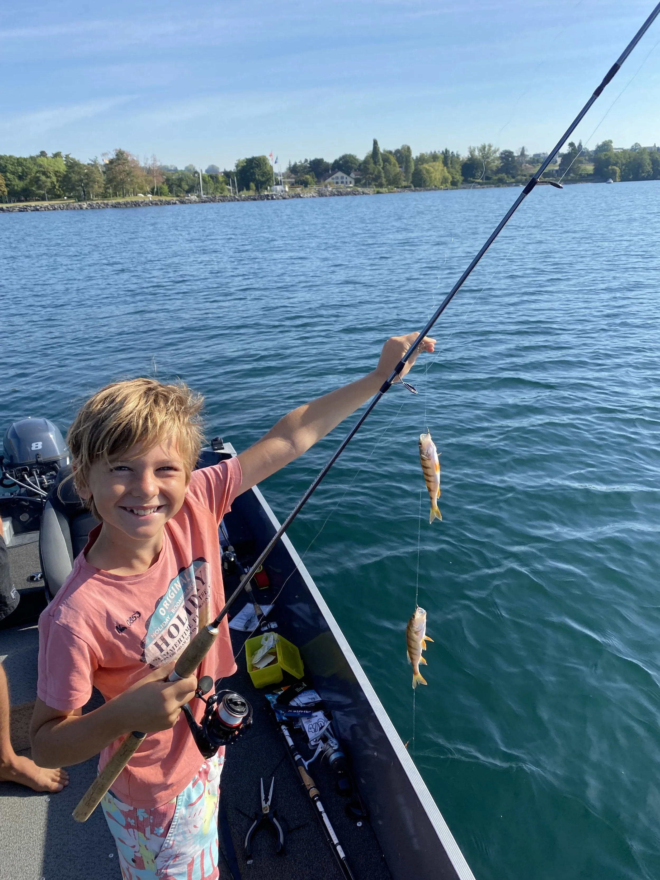 Enfant tenant dans sa main la canne à pêche et les perches qu'il a péchées
