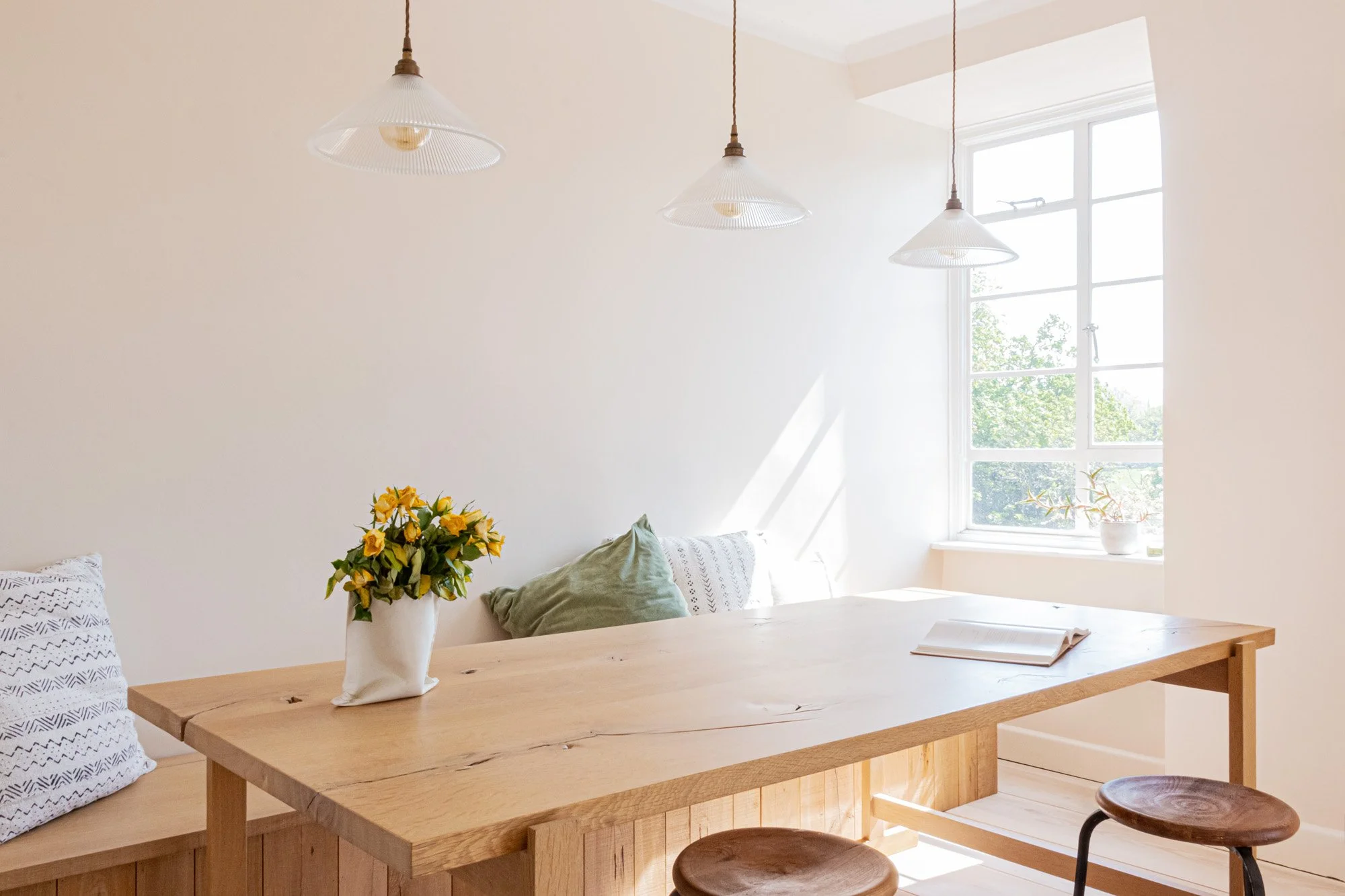 Looking over the oak table top towards a window with sunlight streaming in