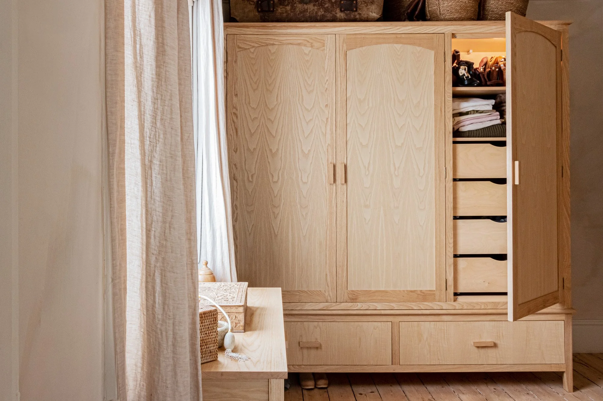 An ash wardrobe with an open door with LED lights illuminating what's inside