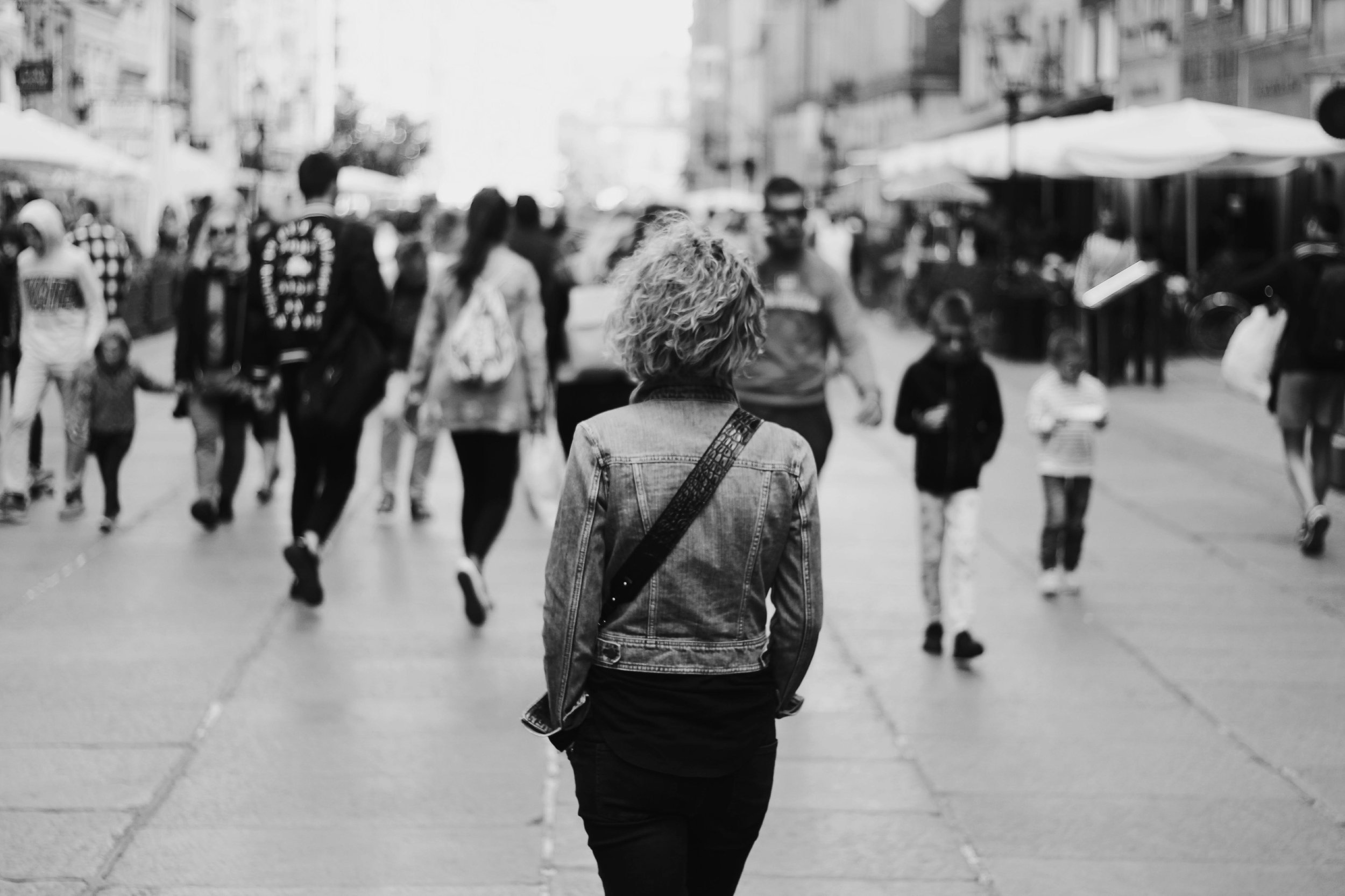A person walking alone through a busy city street, surrounded by people but moving separately
