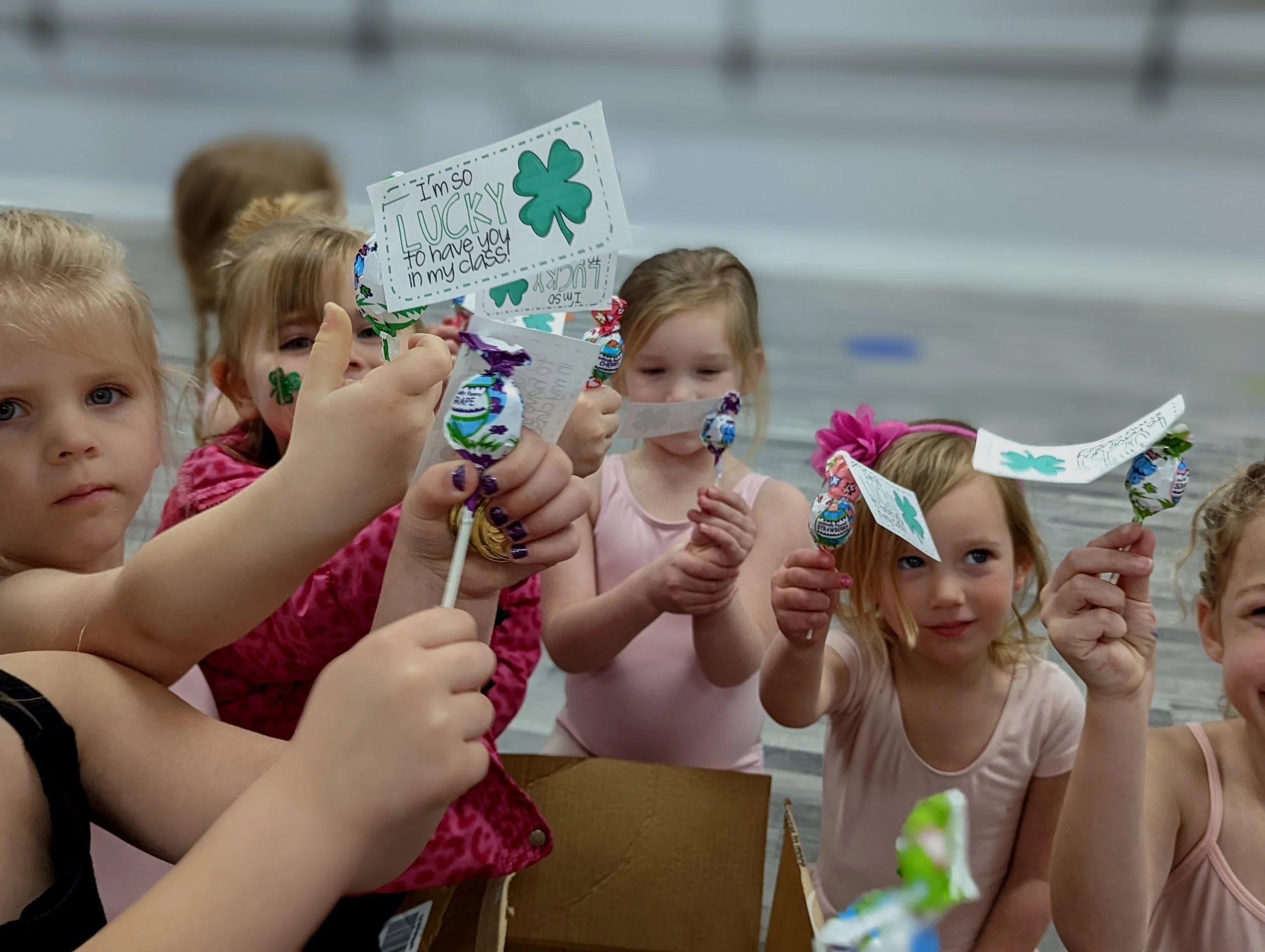 Children sitting at a table, holding small homemade flags with shamrocks, celebrating St. Patrick's Day.