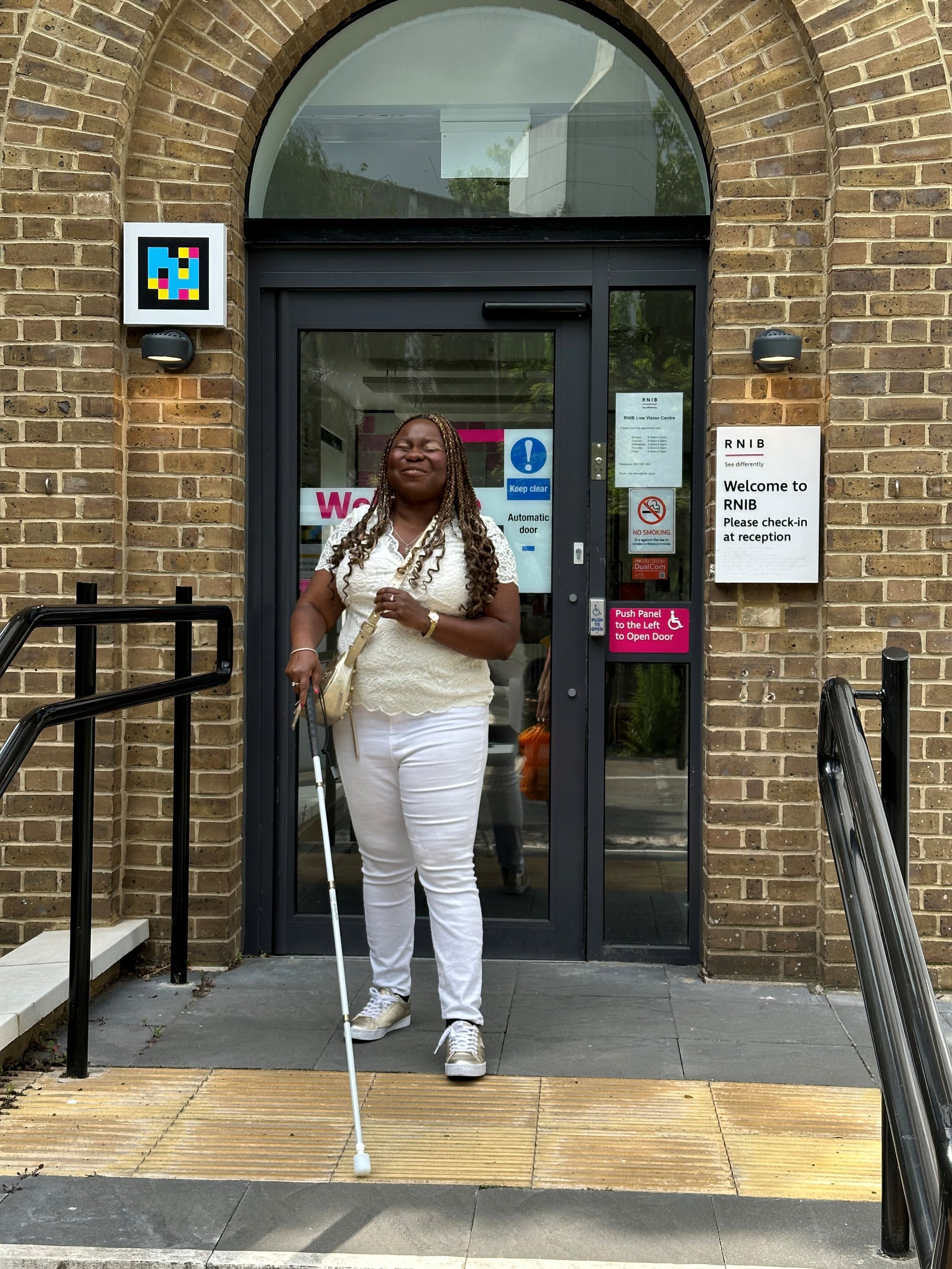 Victoria stood outside the RNIB Building holding a white cane