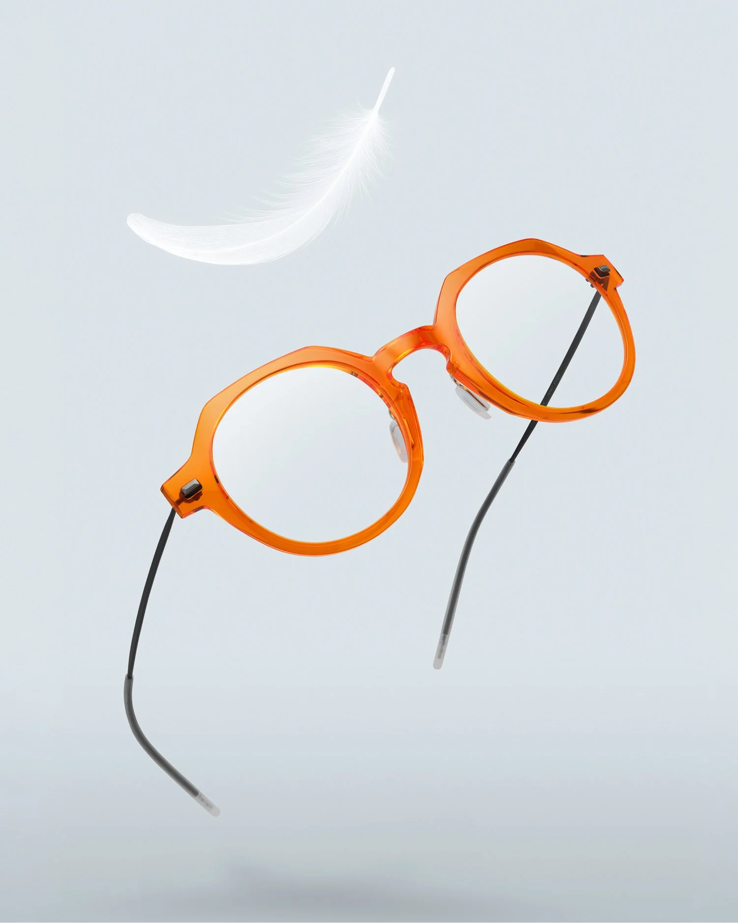 A pair of orange lool eyeglasses with black temples and a white feather floating nearby against a light gray background.
