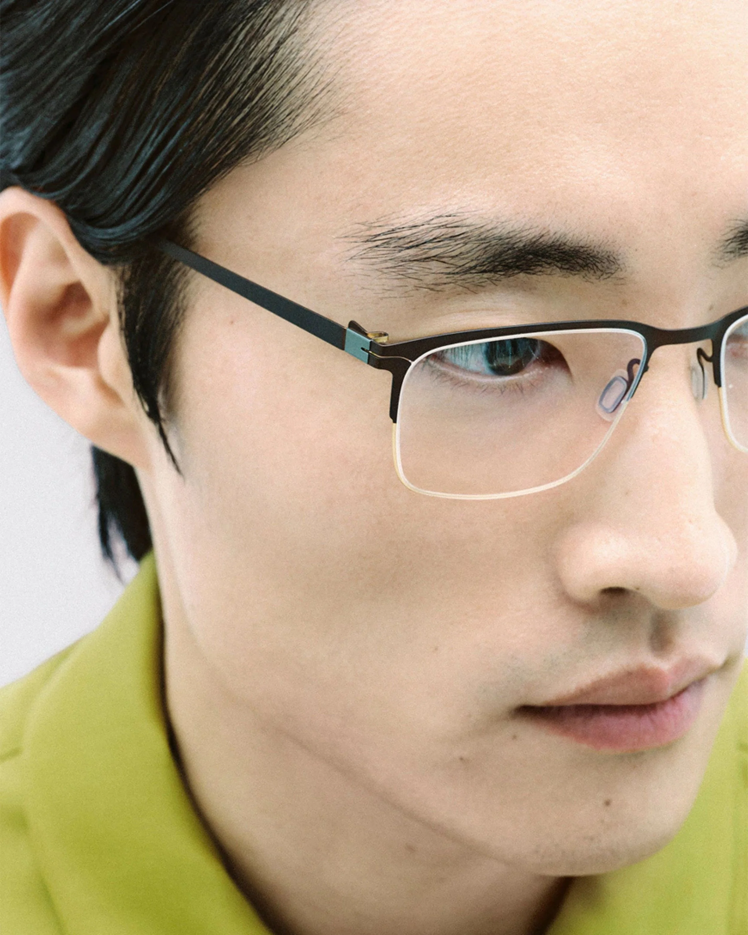Close-up of a person wearing lool glasses and a yellow shirt, with focus on their face and eyeglasses.