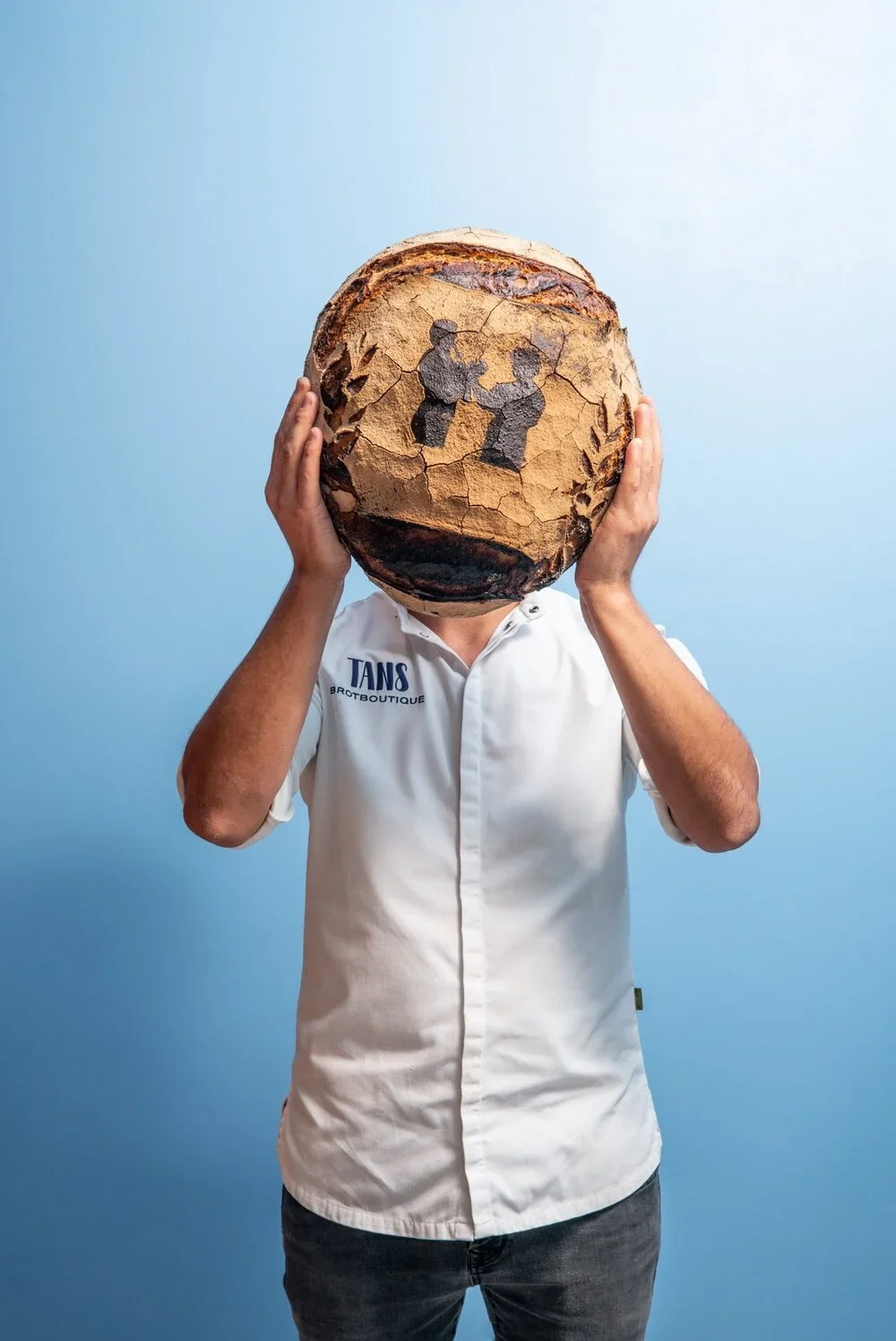 Person mit Fußball, der wie eine erdförmige, alte, rissige Erde aussieht, auf blauer Wand