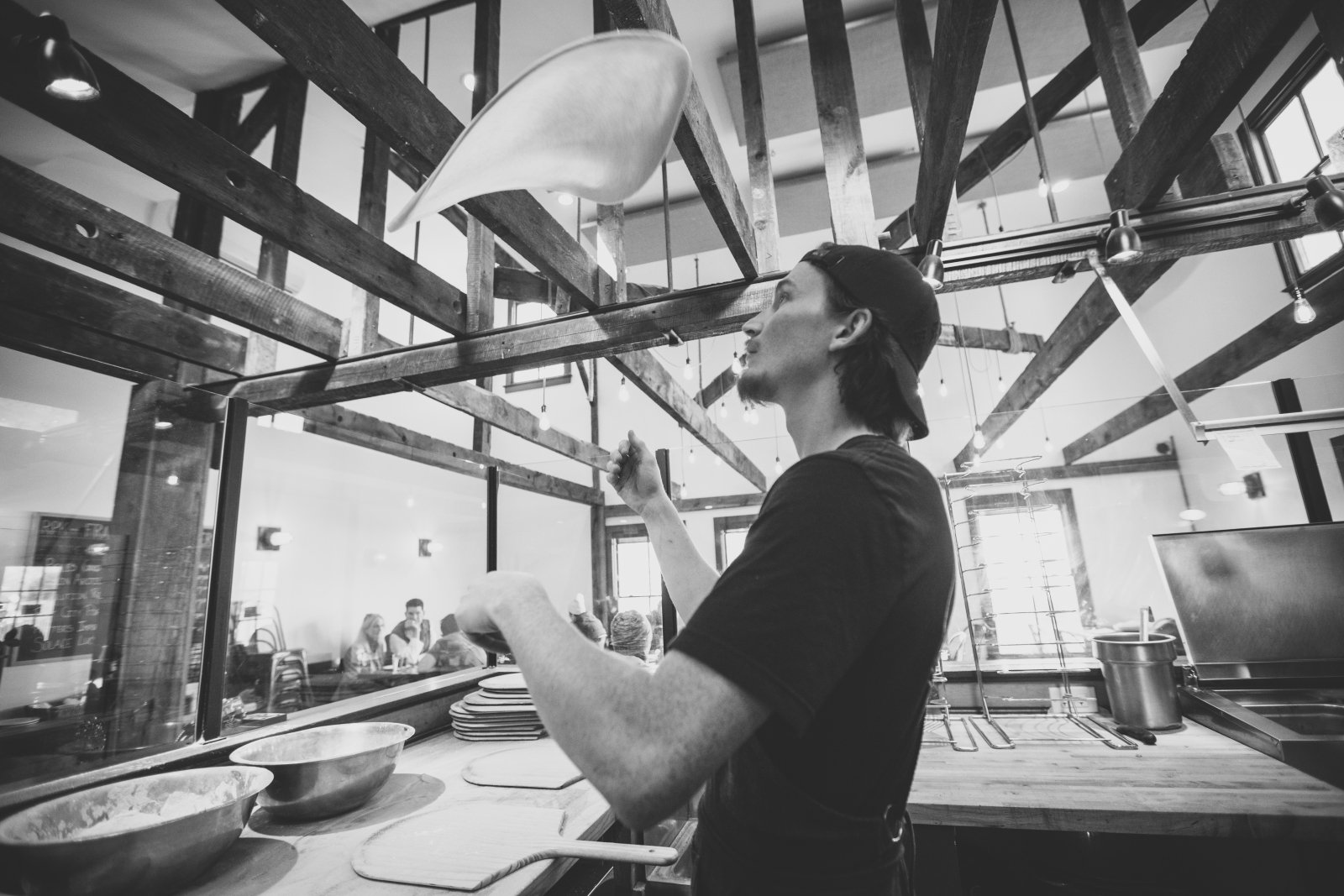 Person holding a round ball of dough in a kitchen.