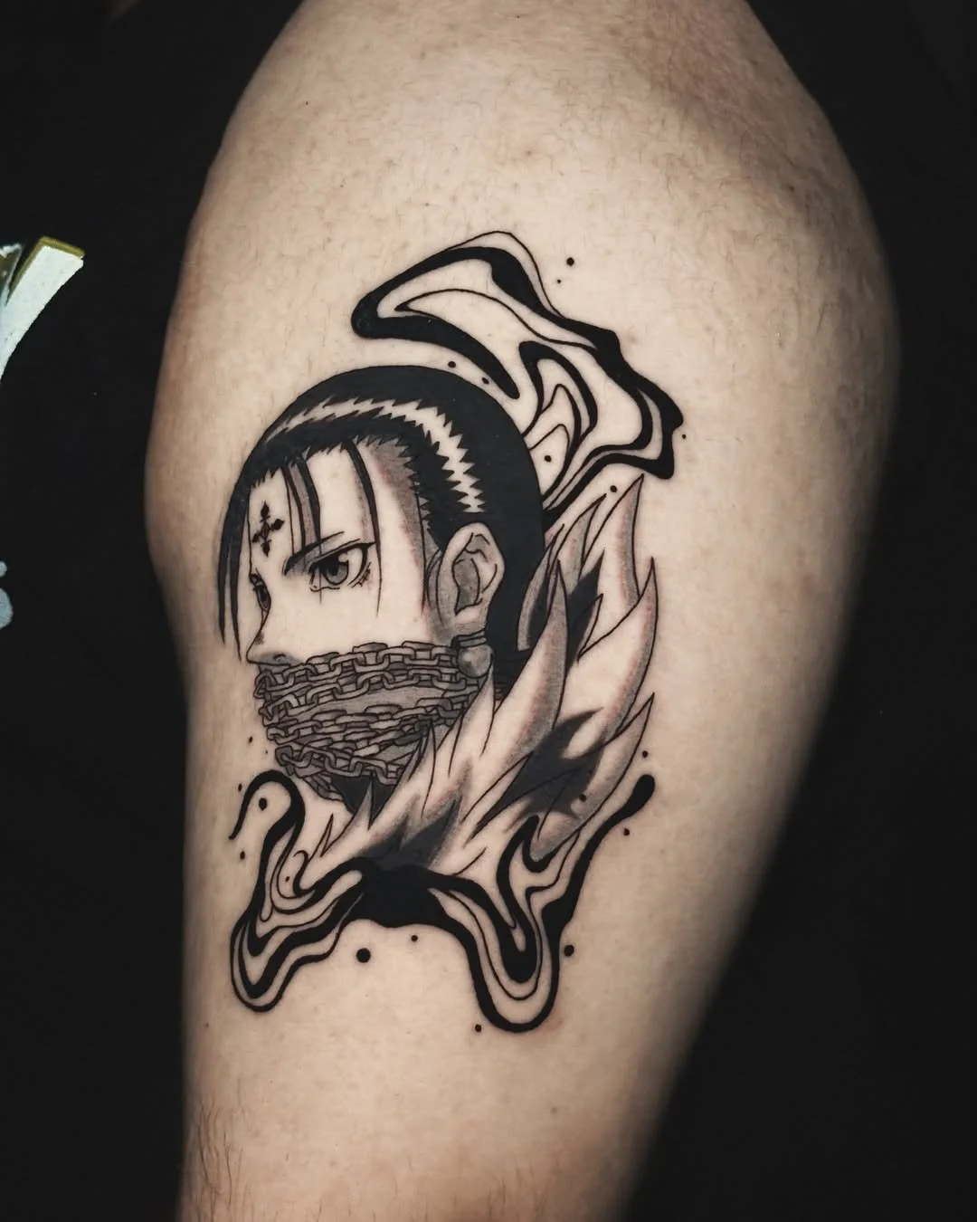 Black and grey illustrative tattoo of Chrollo from Hunter x Hunter, bound by Kurapika's chains and framed in flowing ink. By Stella Sanchez (@umbra.inks), now booking at Dark Water Tattoo Studio in Berkeley.