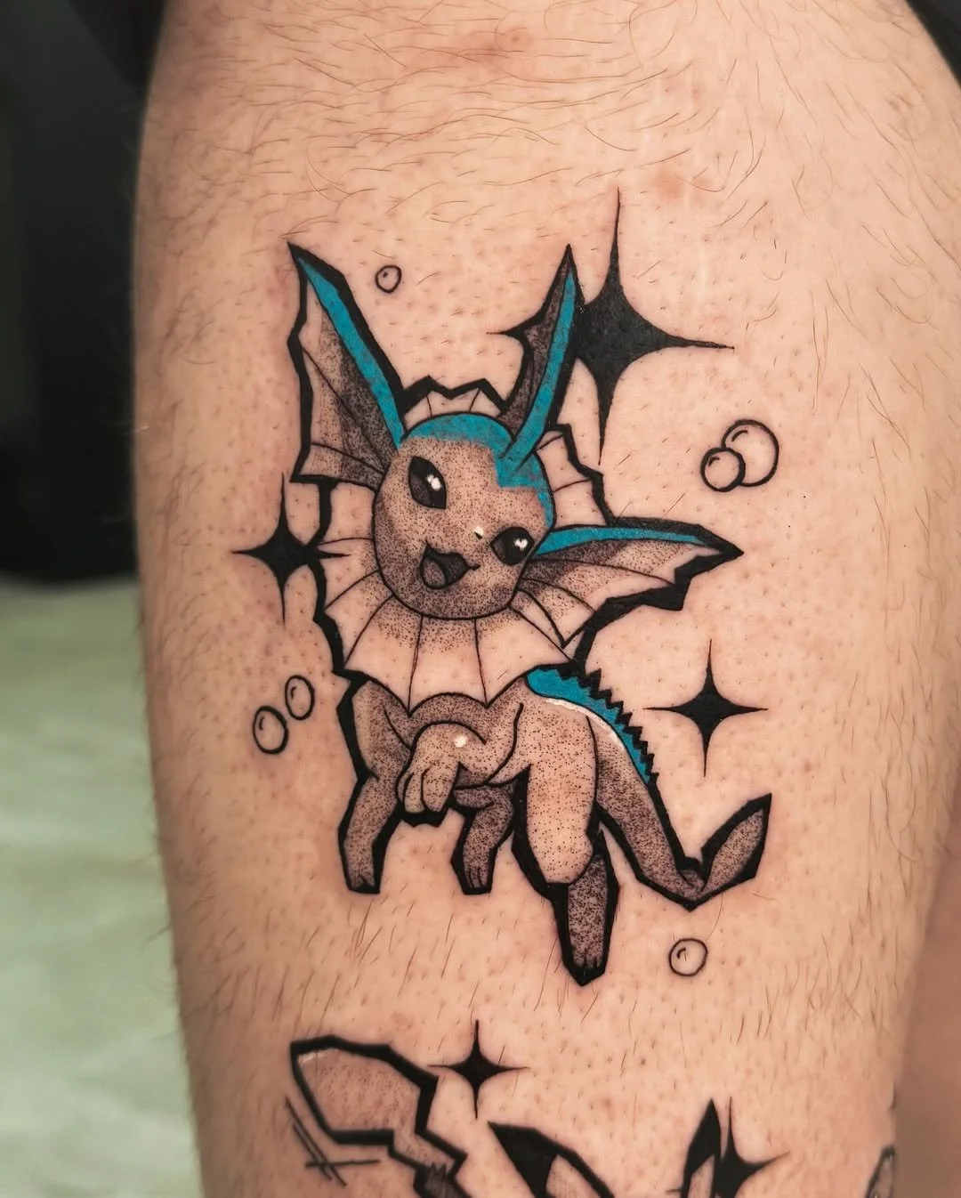 Color Vaporeon tattoo with dotwork shading and bold negative-space sparkles — a fresh take on the classic Eeveelution. By Stella Sanchez (@umbra.inks), now booking at Dark Water Tattoo Studio in Berkeley.