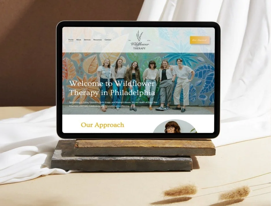 Tablet displaying the homepage of Wildflower Therapy in Philadelphia, with a group of women standing in front of a colorful mural.