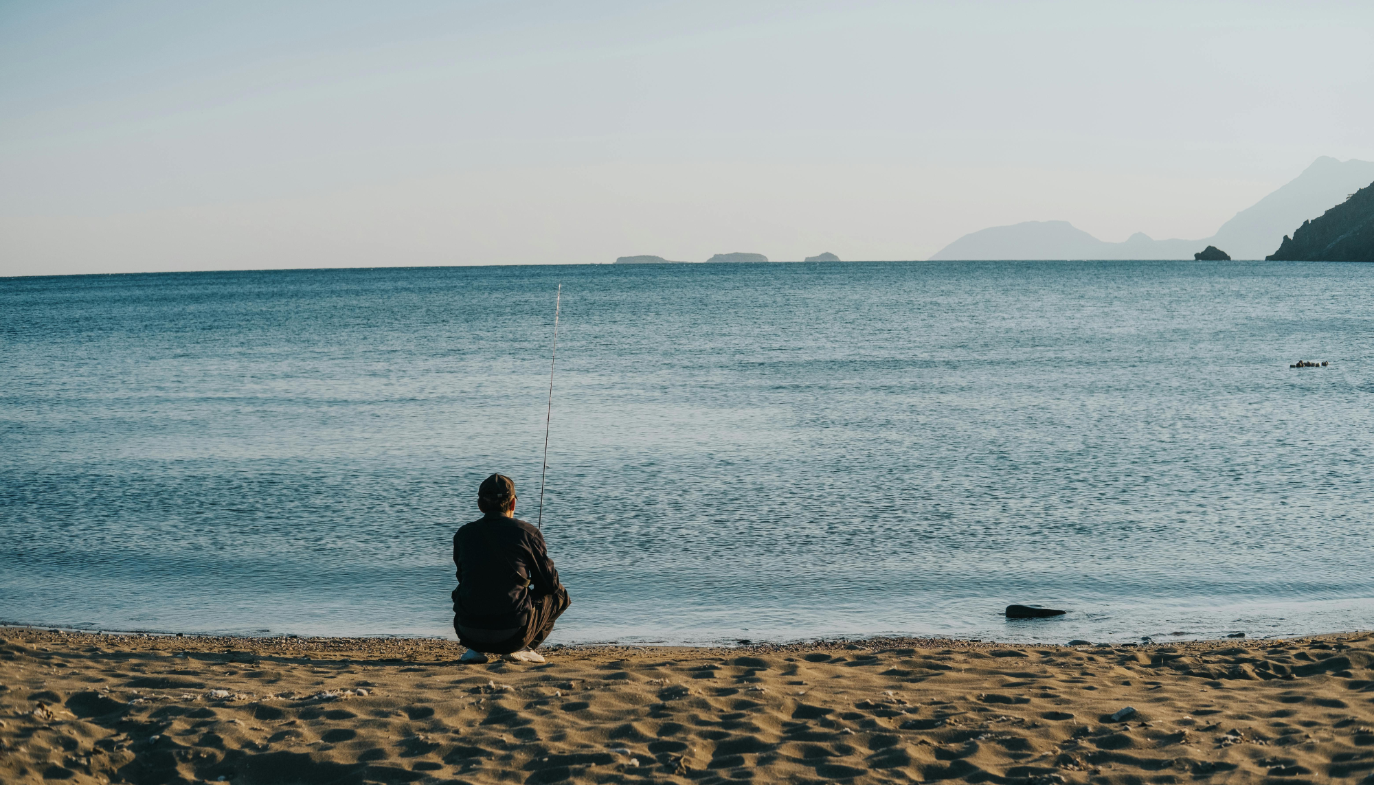 1. Person sitting alone by the ocean, representing grief, loneliness, reflection, and the emotional process of coping with loss.