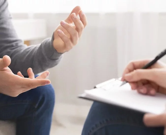 Therapist taking notes while speaking with a client during a counseling session at Sharp Wellness & Counseling in Birmingham, Alabama and McKinney, Texas.