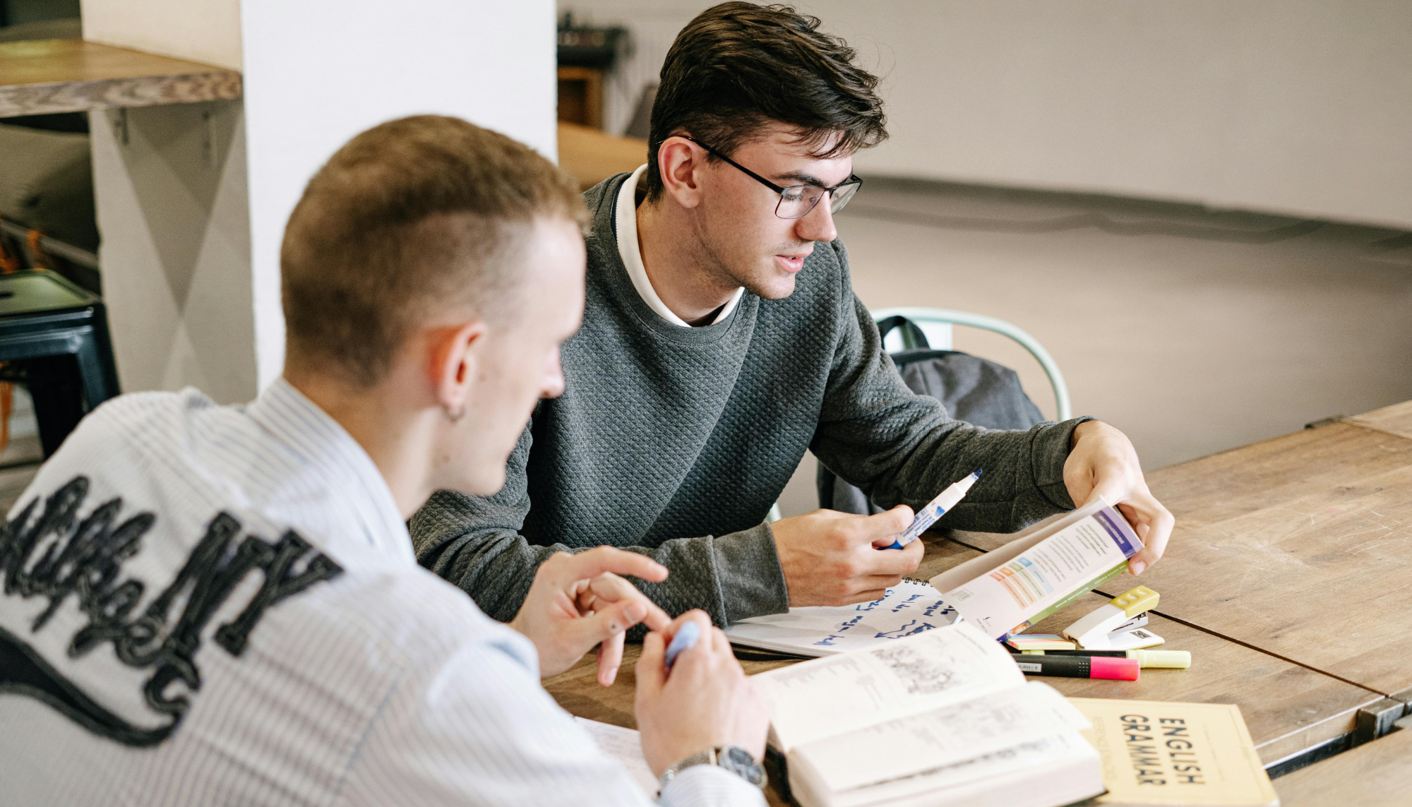 Two men talking and working together at a table, representing men’s therapy for stress, communication, life transitions, and emotional support.
