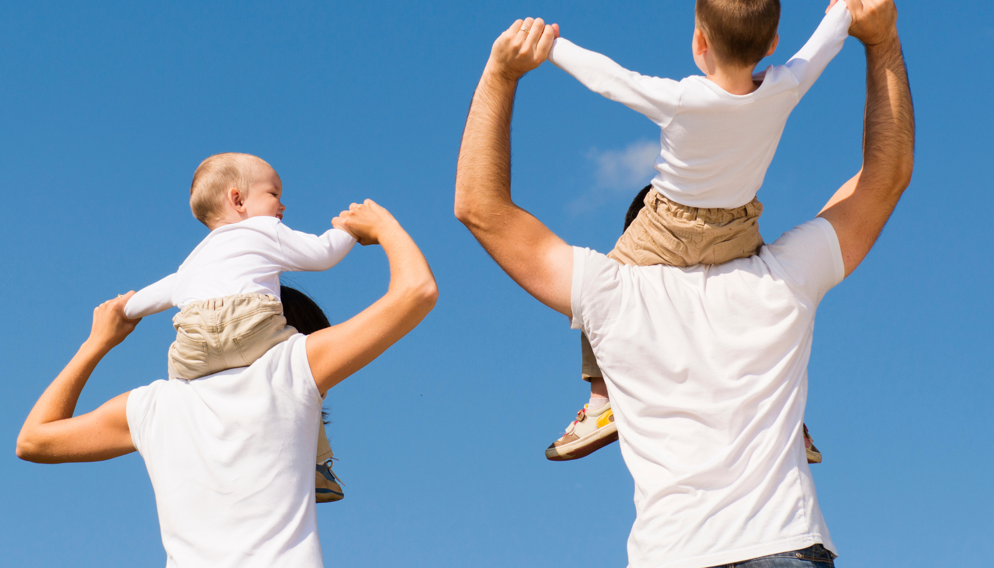 Parents carrying their young children outdoors, representing family connection, parenting support, and parent therapy.