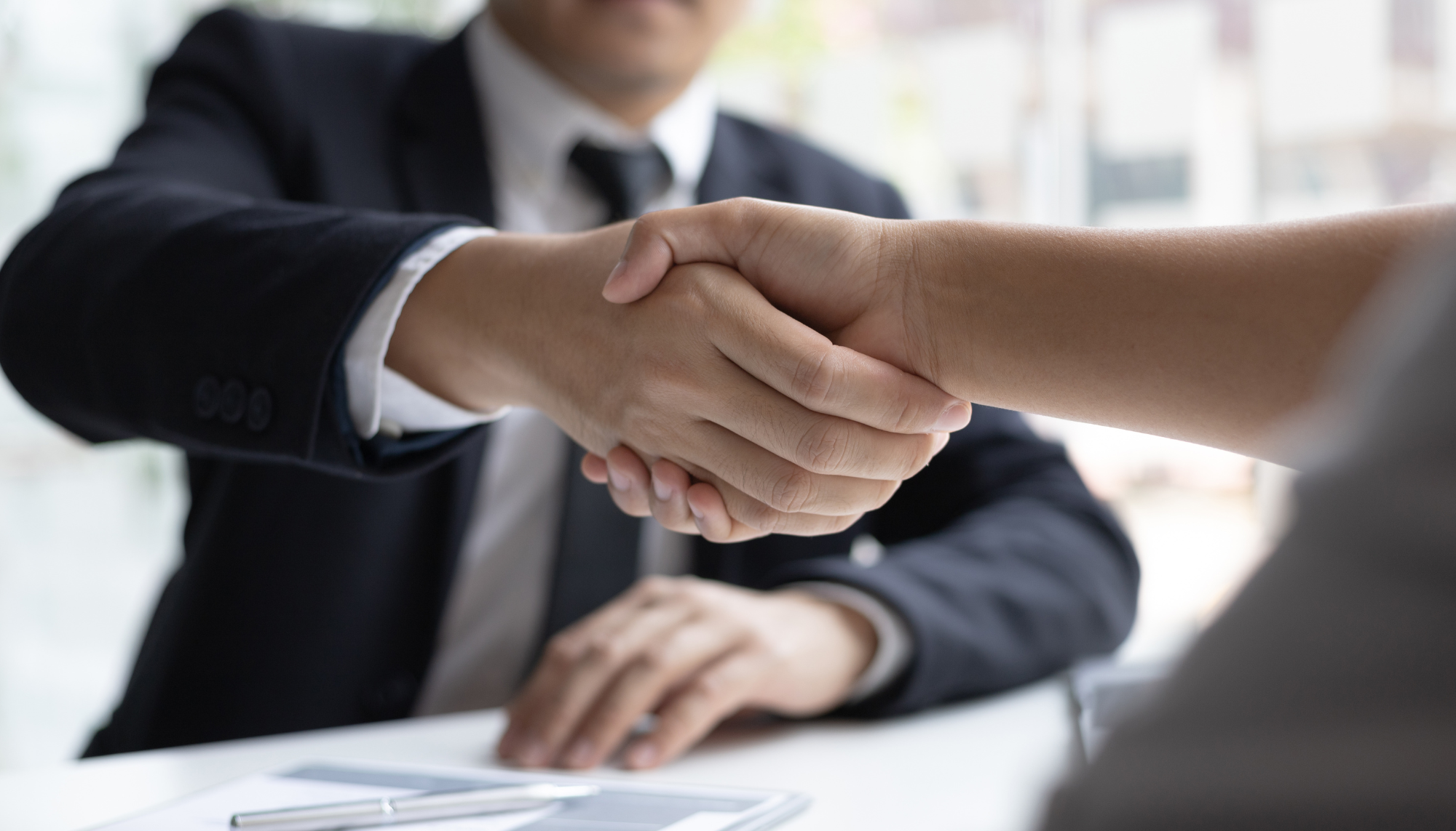 Professional handshake representing career changes, new opportunities, and life transitions therapy for adults navigating work and major life changes.