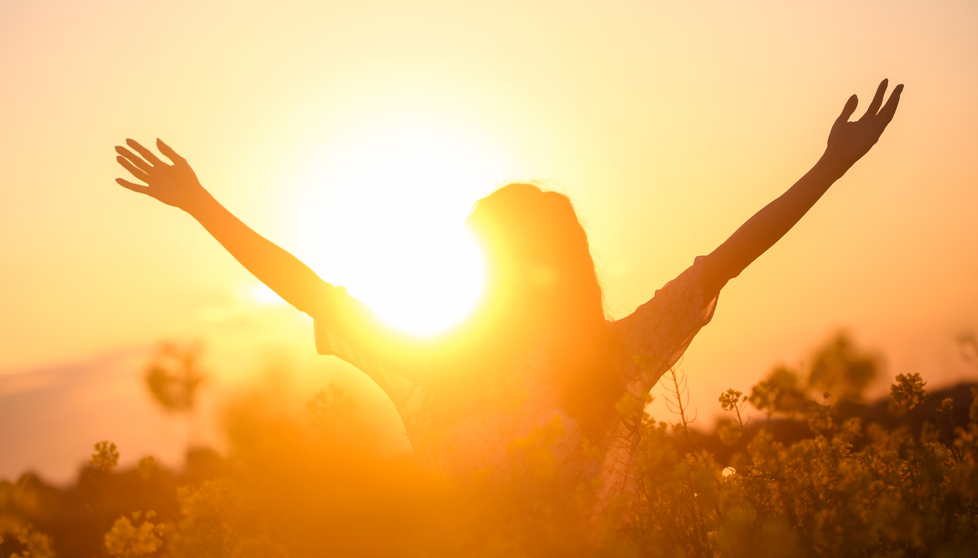 Person standing outdoors in warm sunlight with arms raised, representing hope, healing, and emotional wellness through depression therapy.