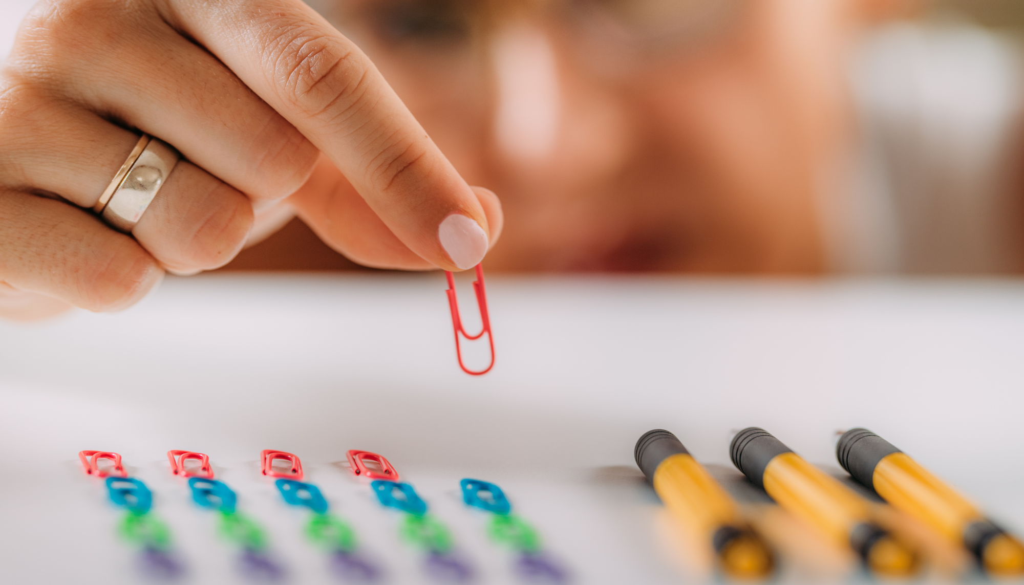 Person carefully organizing paper clips in a precise pattern, representing repetitive behaviors, order, and compulsions associated with OCD.