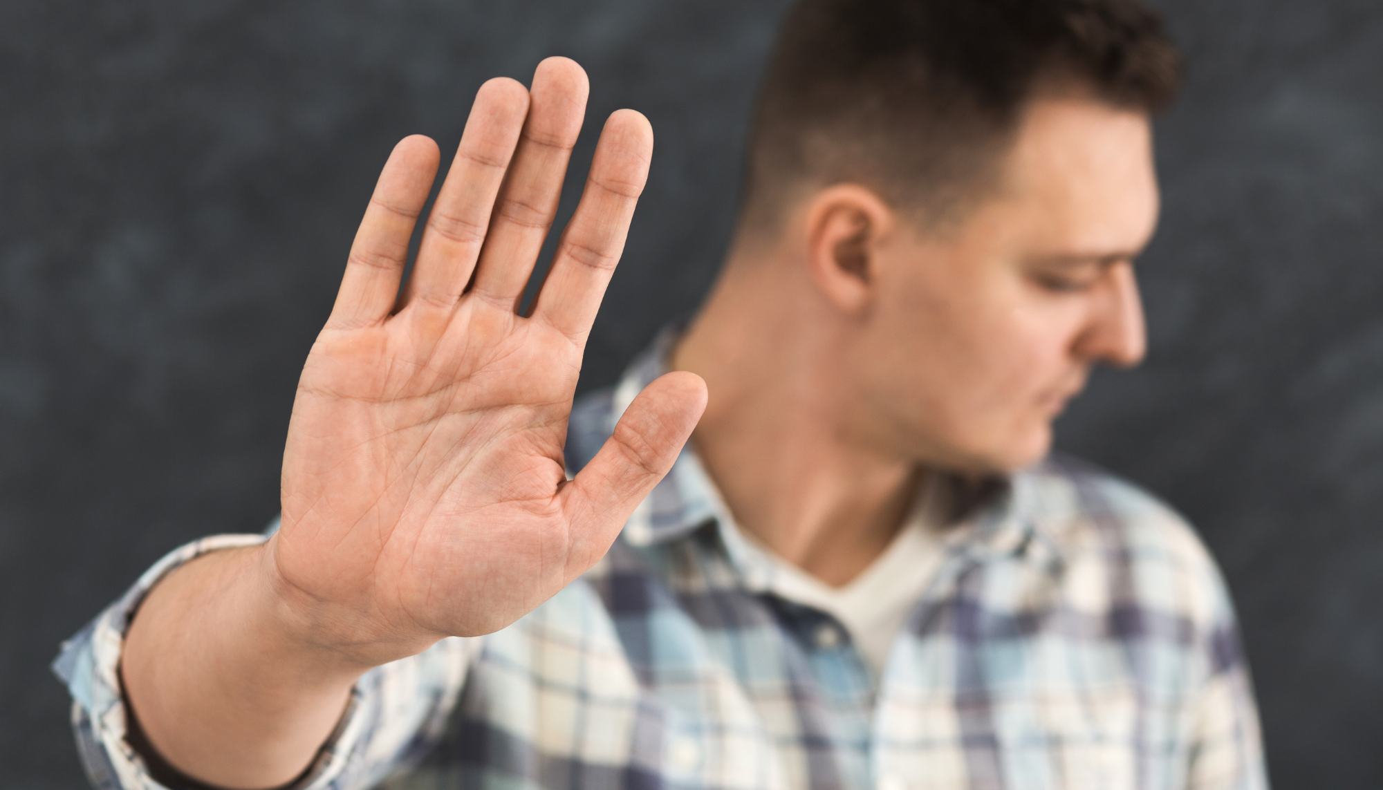 Man setting a boundary with his hand raised, representing people pleasing, difficulty saying no, perfectionism, and learning healthy boundaries in therapy.