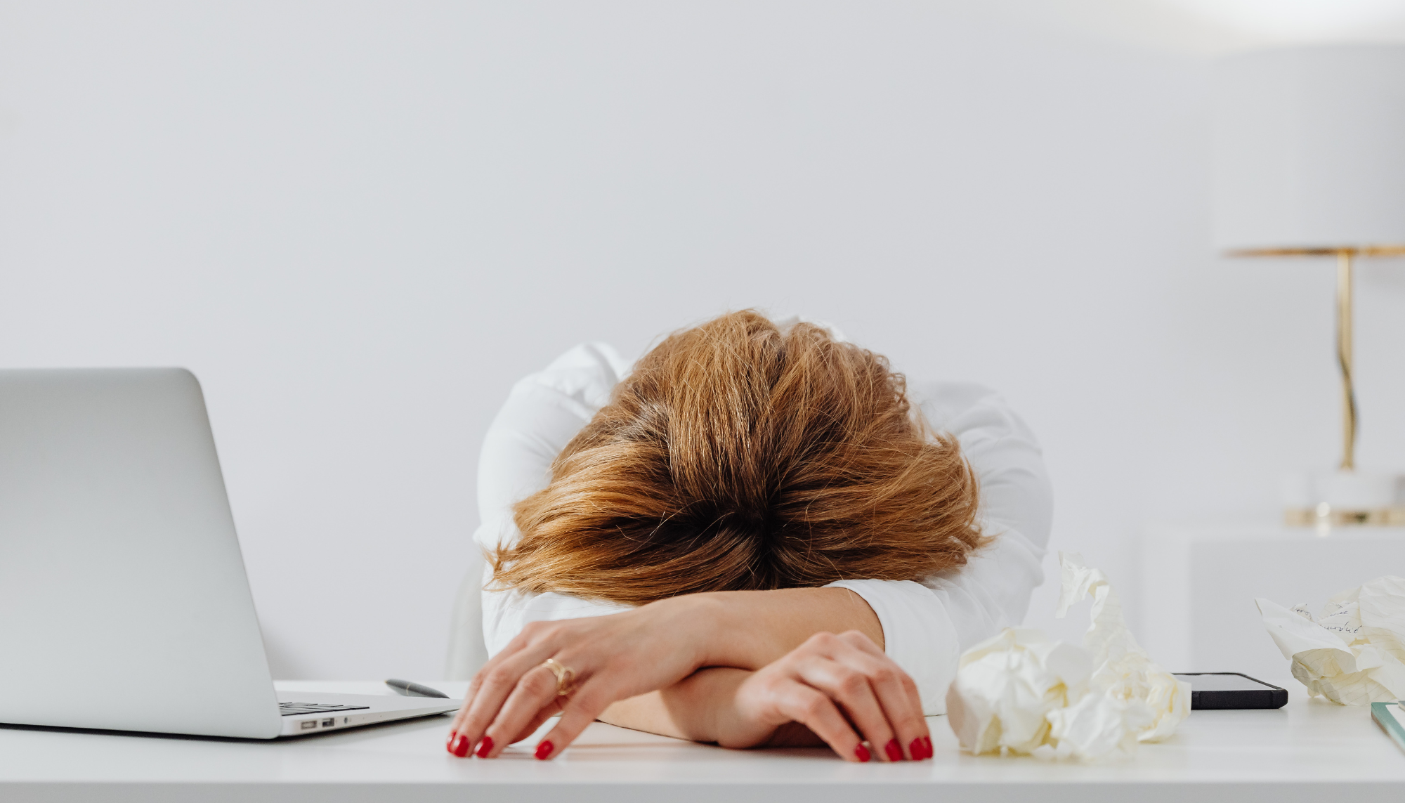 Person sitting at a desk with their head resting on folded arms beside a laptop, appearing emotionally exhausted and overwhelmed, representing emotional burnout, chronic stress, and mental fatigue.
