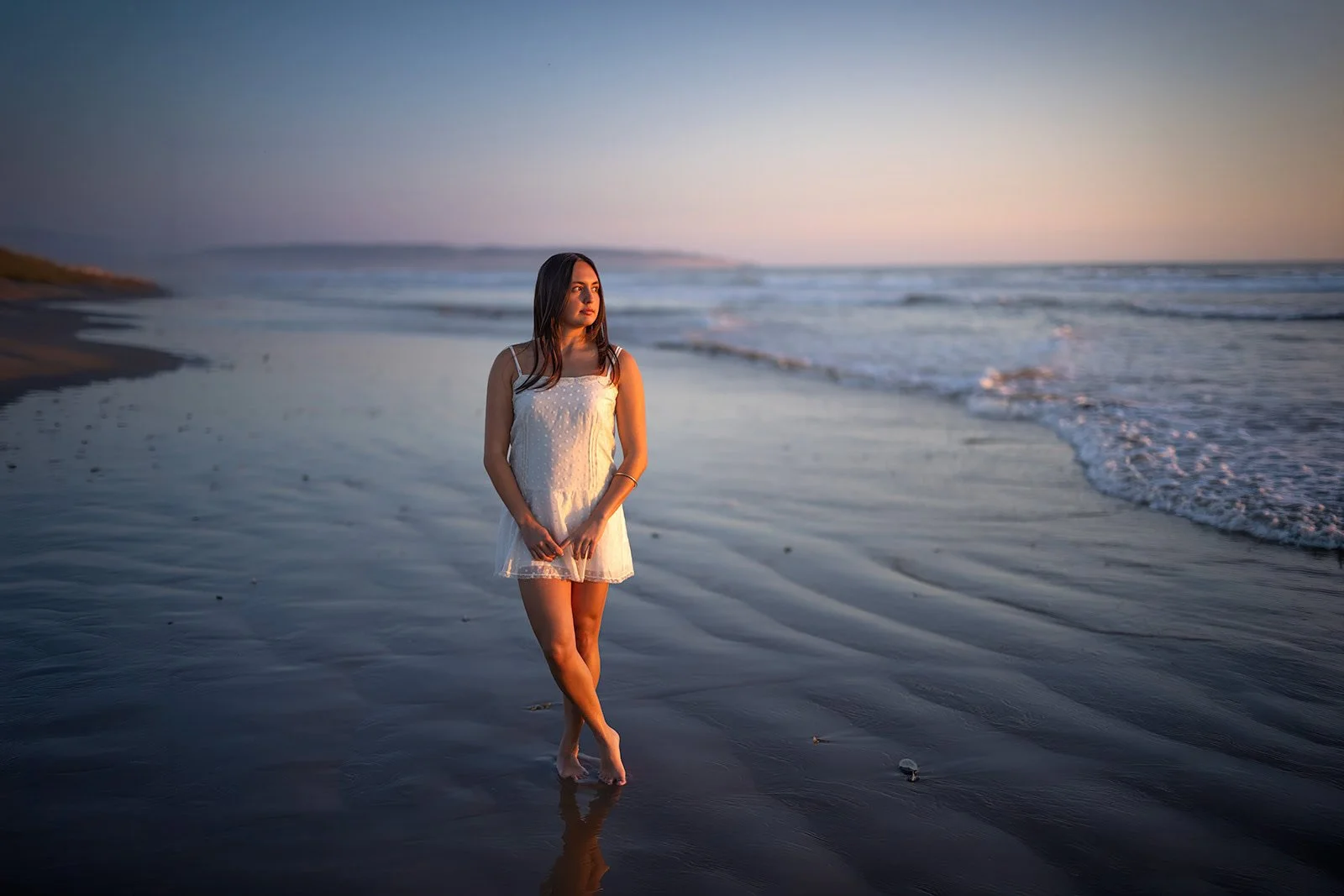 Cal Poly senior wearing a white skirt during a moody blue-hour beach portrait session