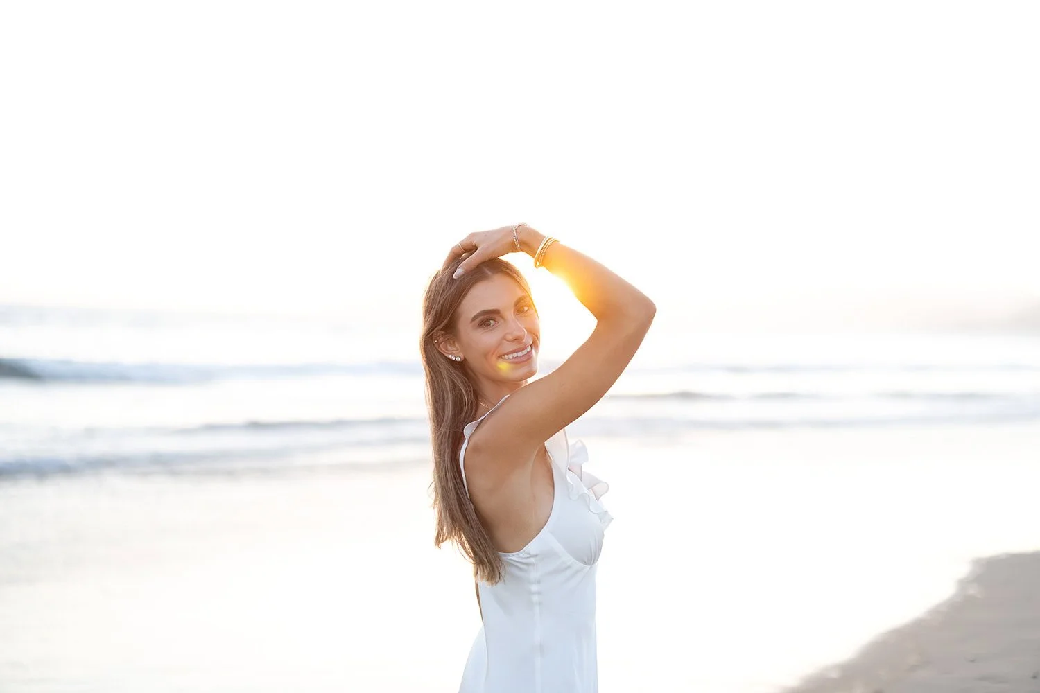 Cal Poly senior girl standing on the beach with sunlight illuminating her face
