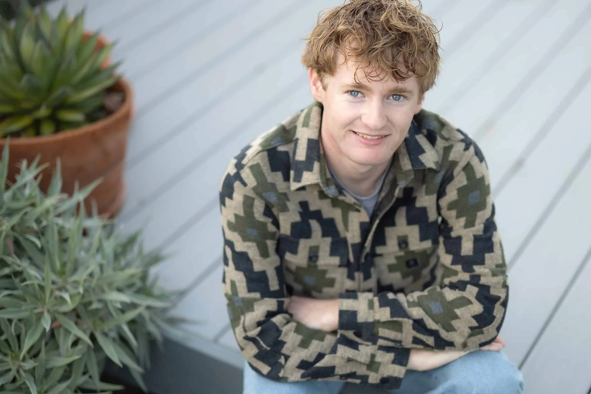 High school senior relaxed on a sunlit deck among succulents and native plants, creating a calm, natural portrait in San Luis Obispo.