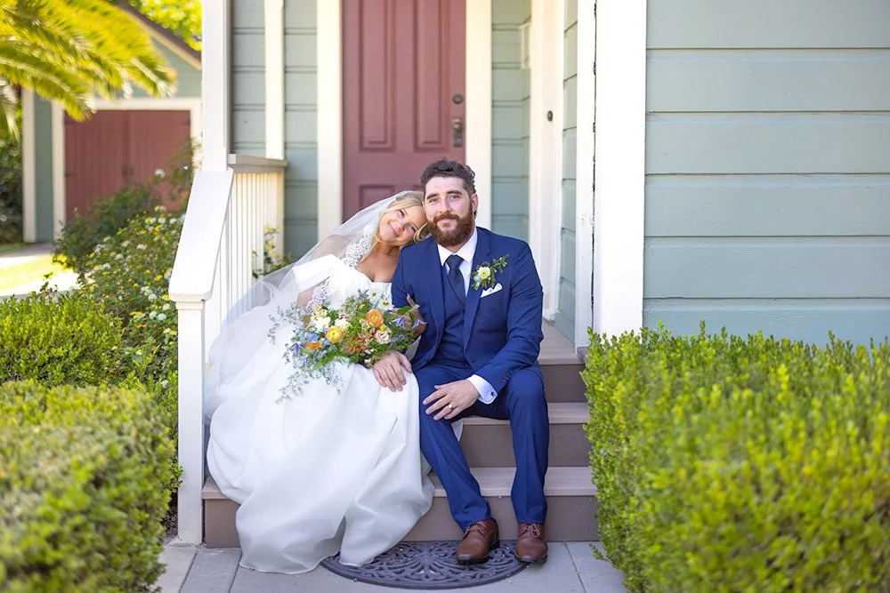 Newlywed bride leaning on her husband’s shoulder while holding her bouquet on the Heritage House porch in Arroyo Grande, California