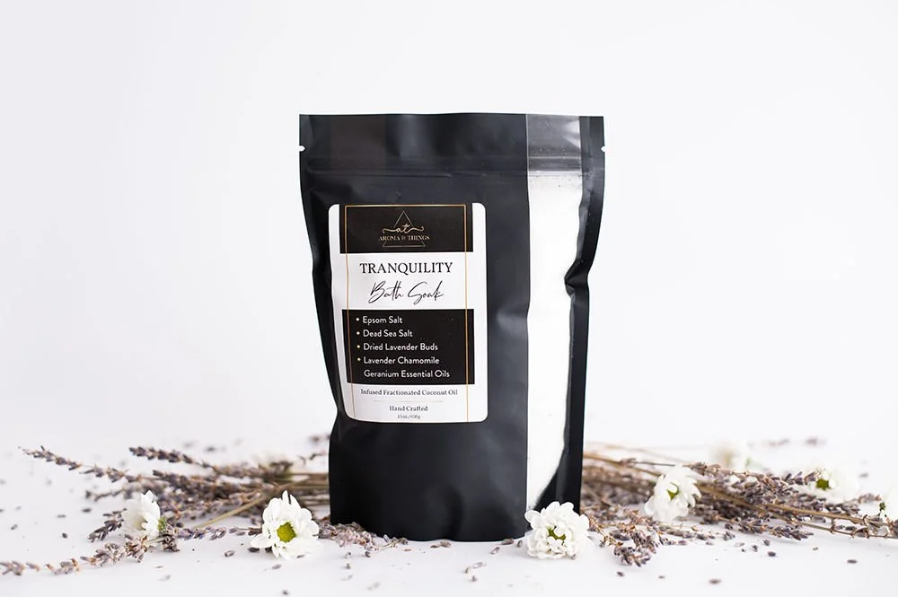 Tranquility aromatherapy bath soak; black bag, flowers & lavender nearby