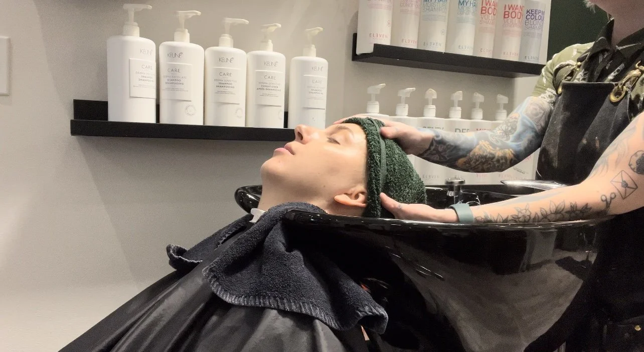 Client receives a relaxing scalp treatment at Fern&Moody Salon in Chicago, featuring Keune Care shampoo products in the background.