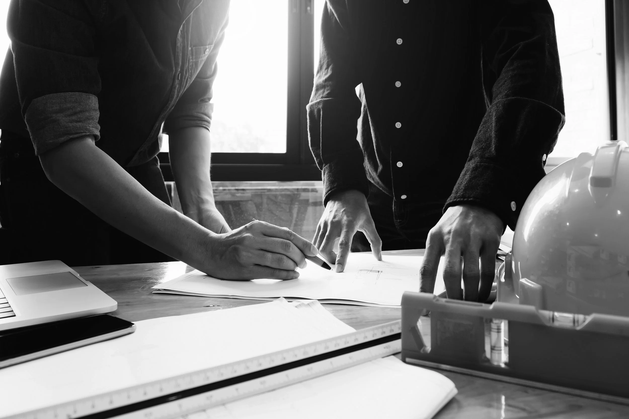 Two engineers consulting on a drawing set