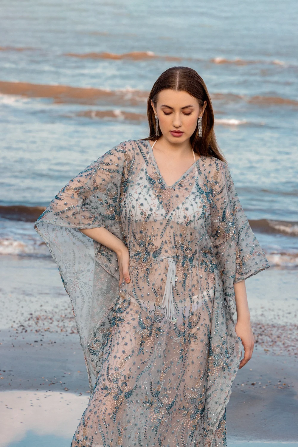 Star of India Kaftan in blue beaded illusion tulle, photographed beside the ocean.