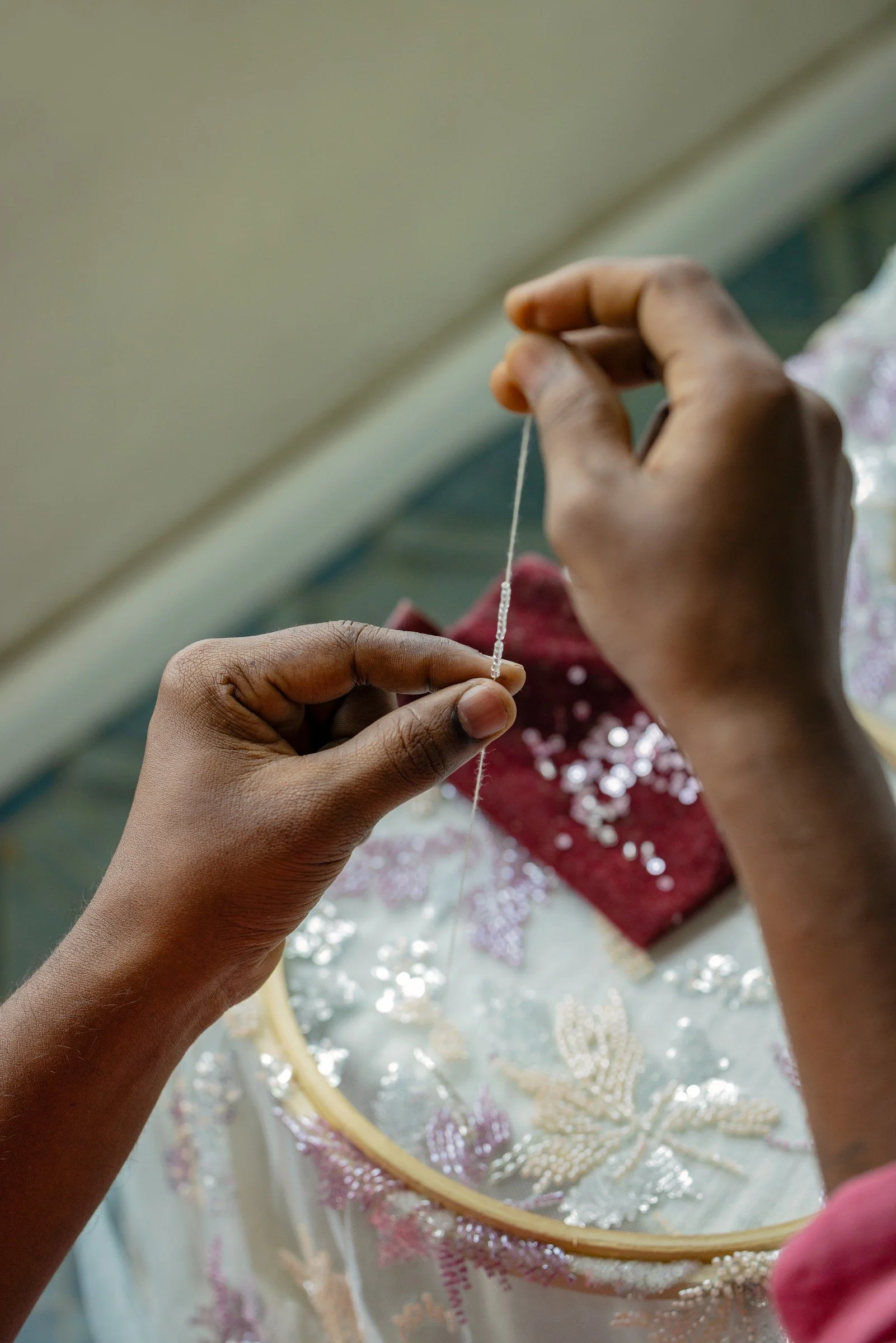 A KUMARI artisan stitching beads by hand into floral embroidery.