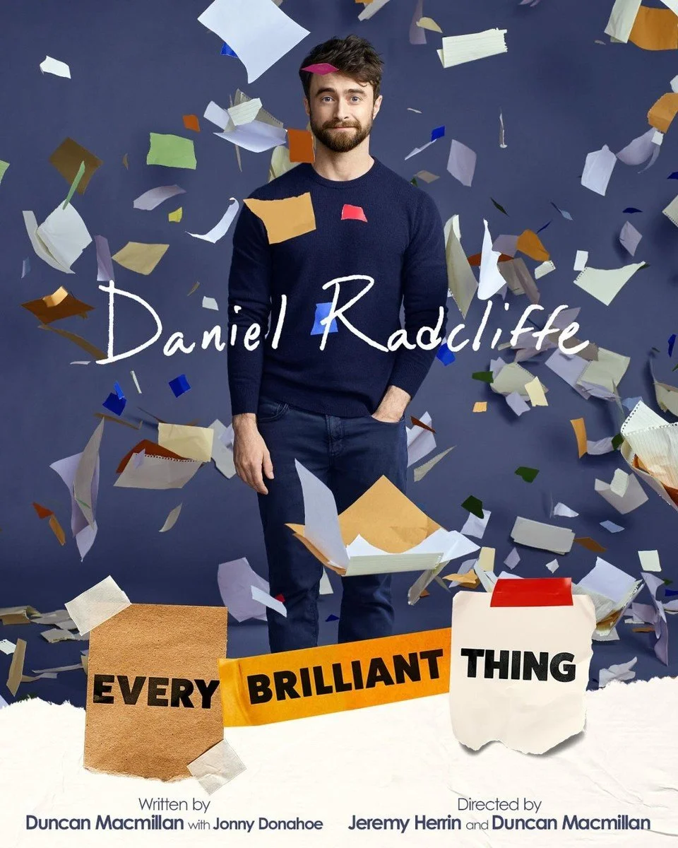 Book cover featuring a man standing amidst flying pages and notes. The man has brown hair and a beard, wearing a navy sweater and jeans, with a slight smile. The background is dark blue. The title reads "Every Brilliant Thing" and is written in a mix