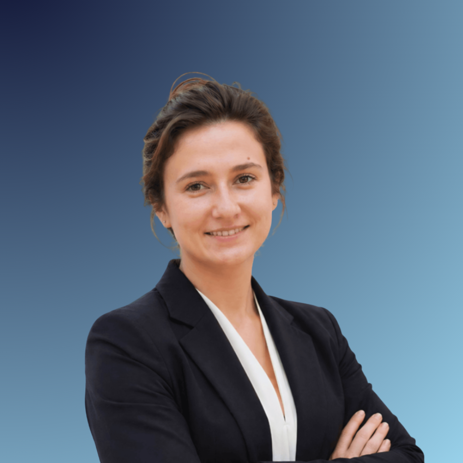 Portrait of a young woman with short brown hair, wearing a black blazer and a white blouse, standing with arms crossed and smiling.