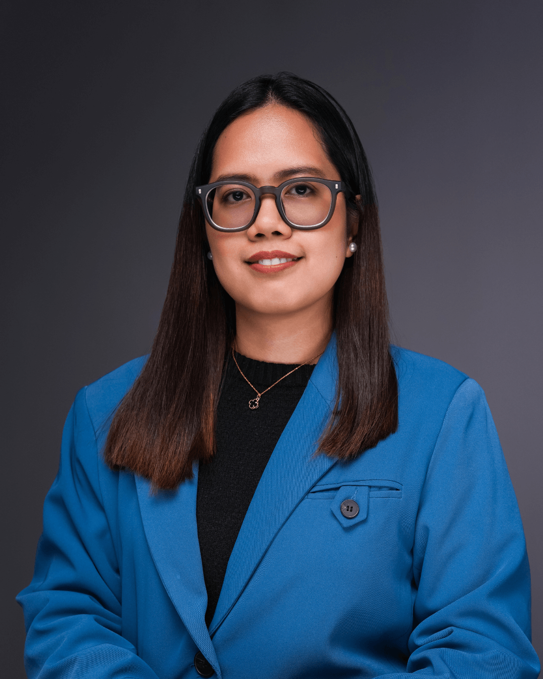 A woman wearing glasses dressed in a bright blue suit.