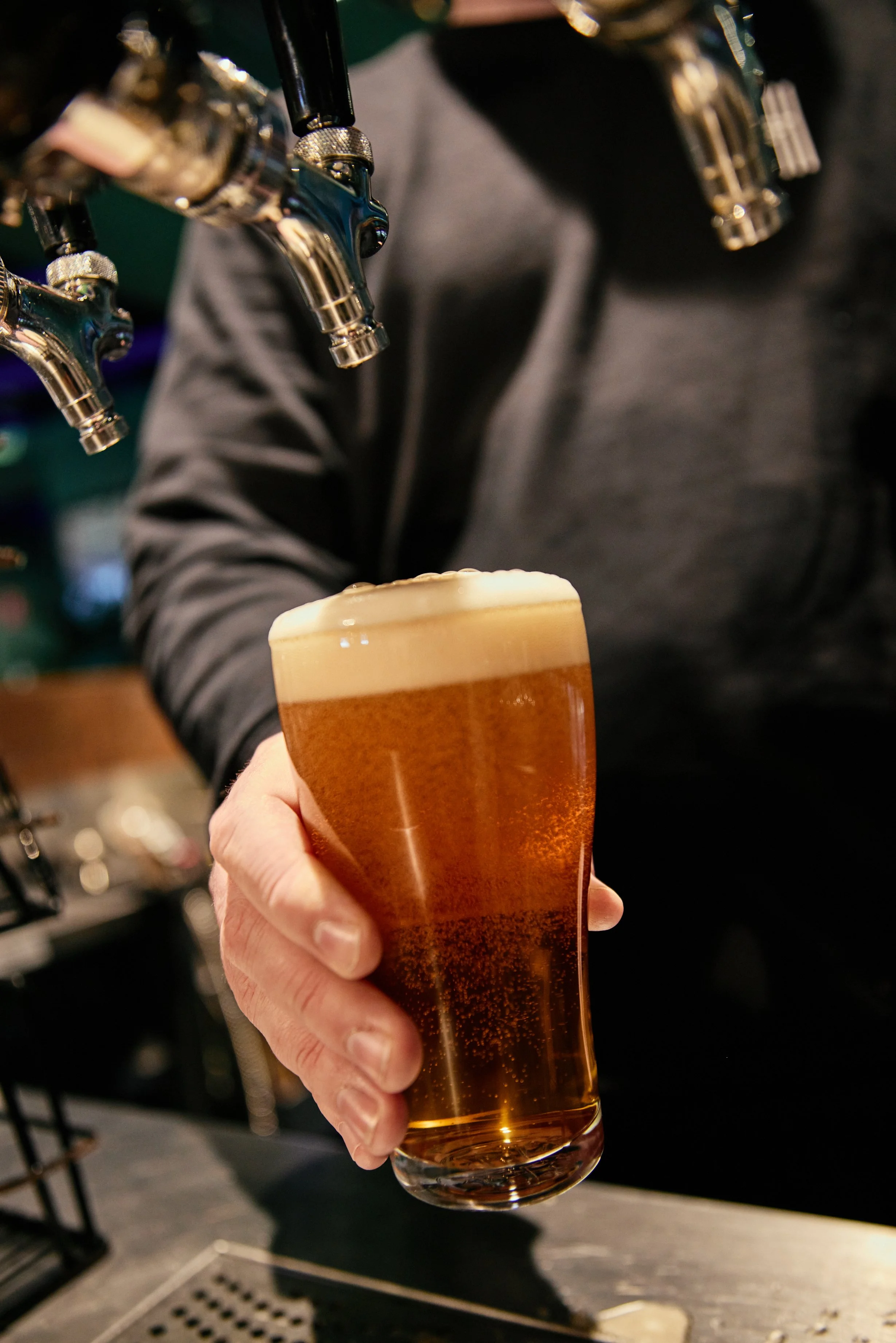 A bartender holding a schooner of beer under a tap at Hightail Bar in the Docklands.