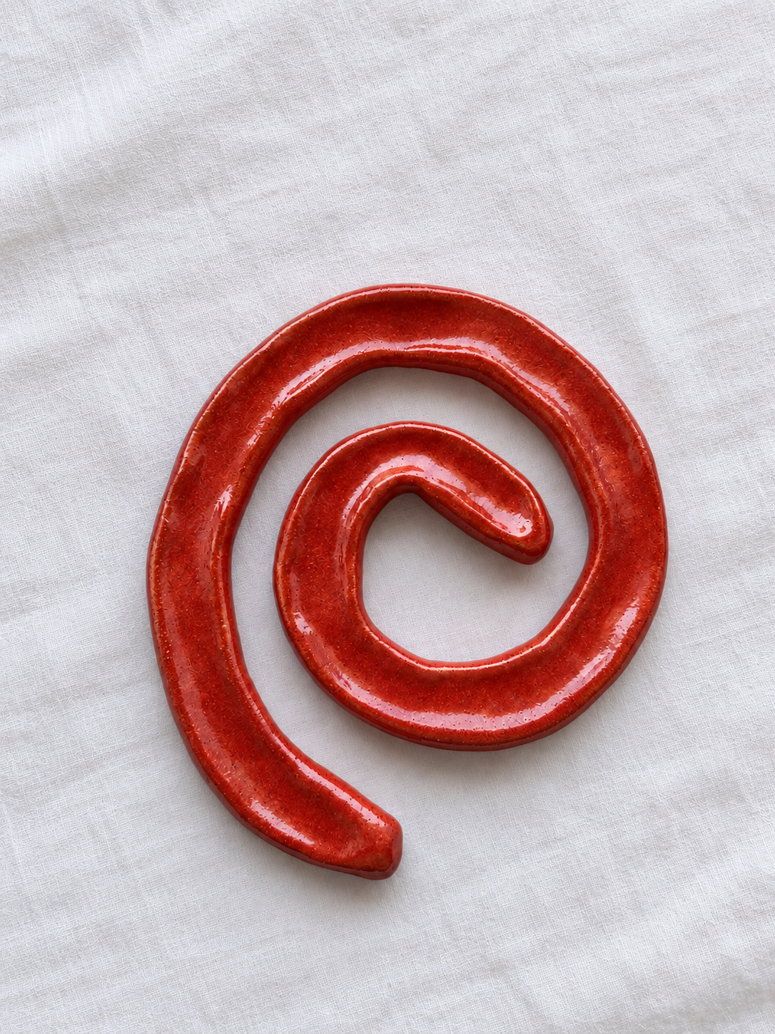 Brick-red swirl dish on white linen (1).png