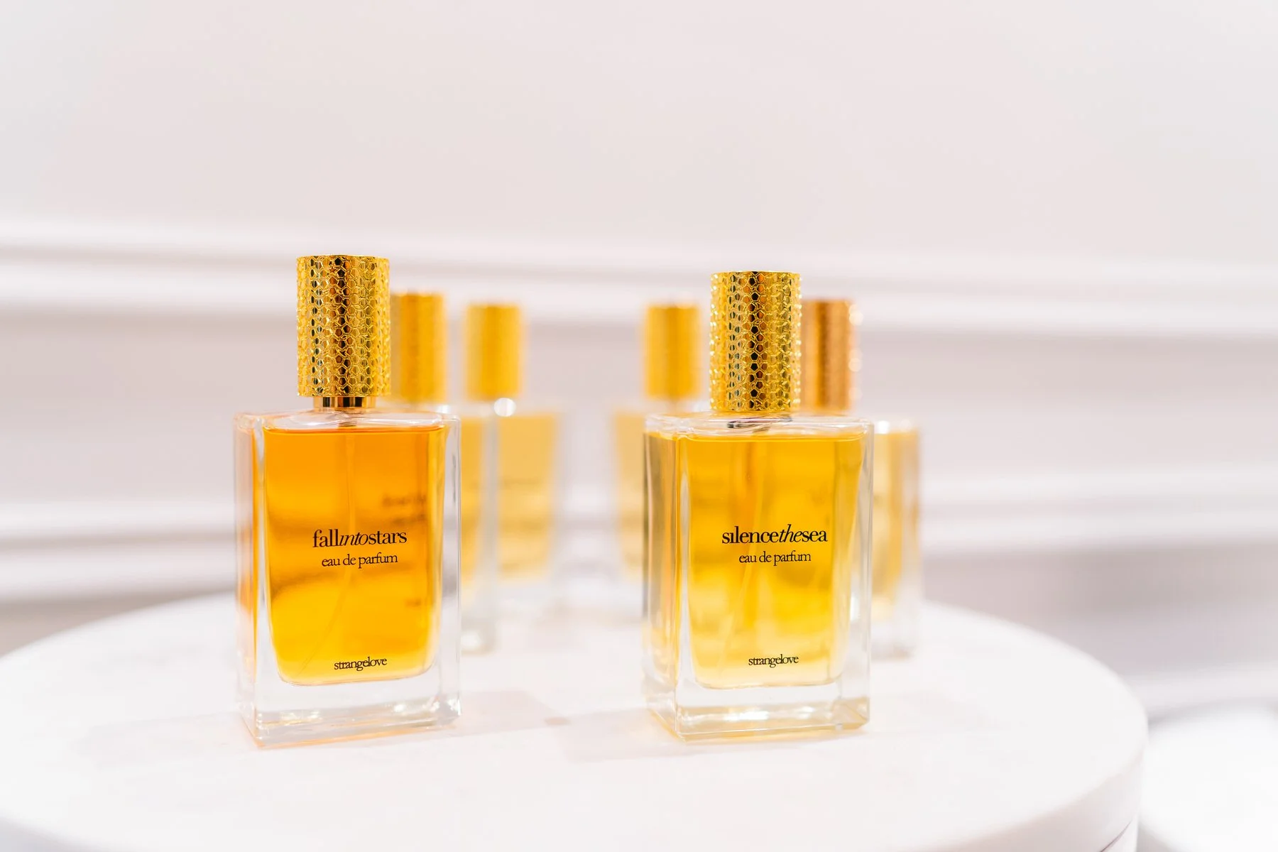 Frascos de perfume con aroma amarillo en un exhibidor blanco.