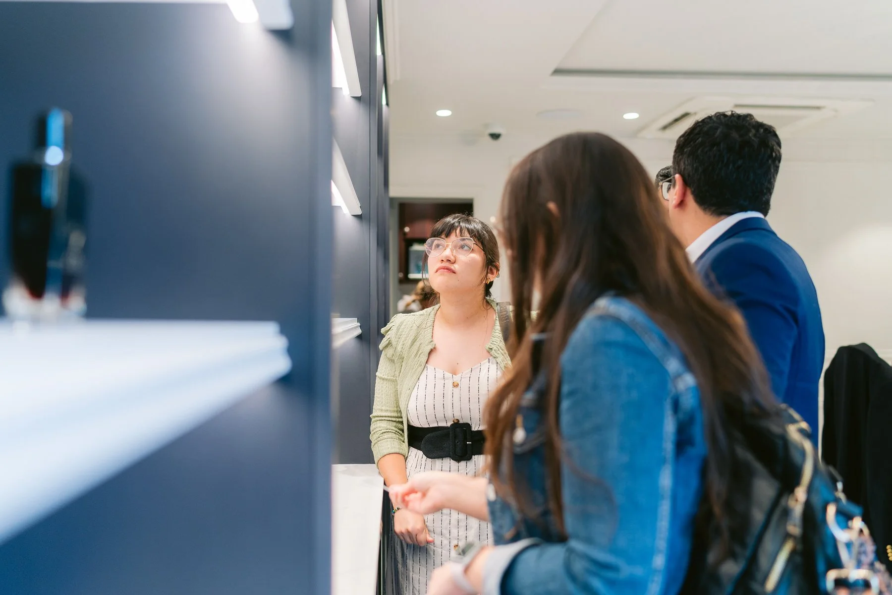 Personas en una recepción o mostrador en un entorno moderno, conversando y esperando atención.
