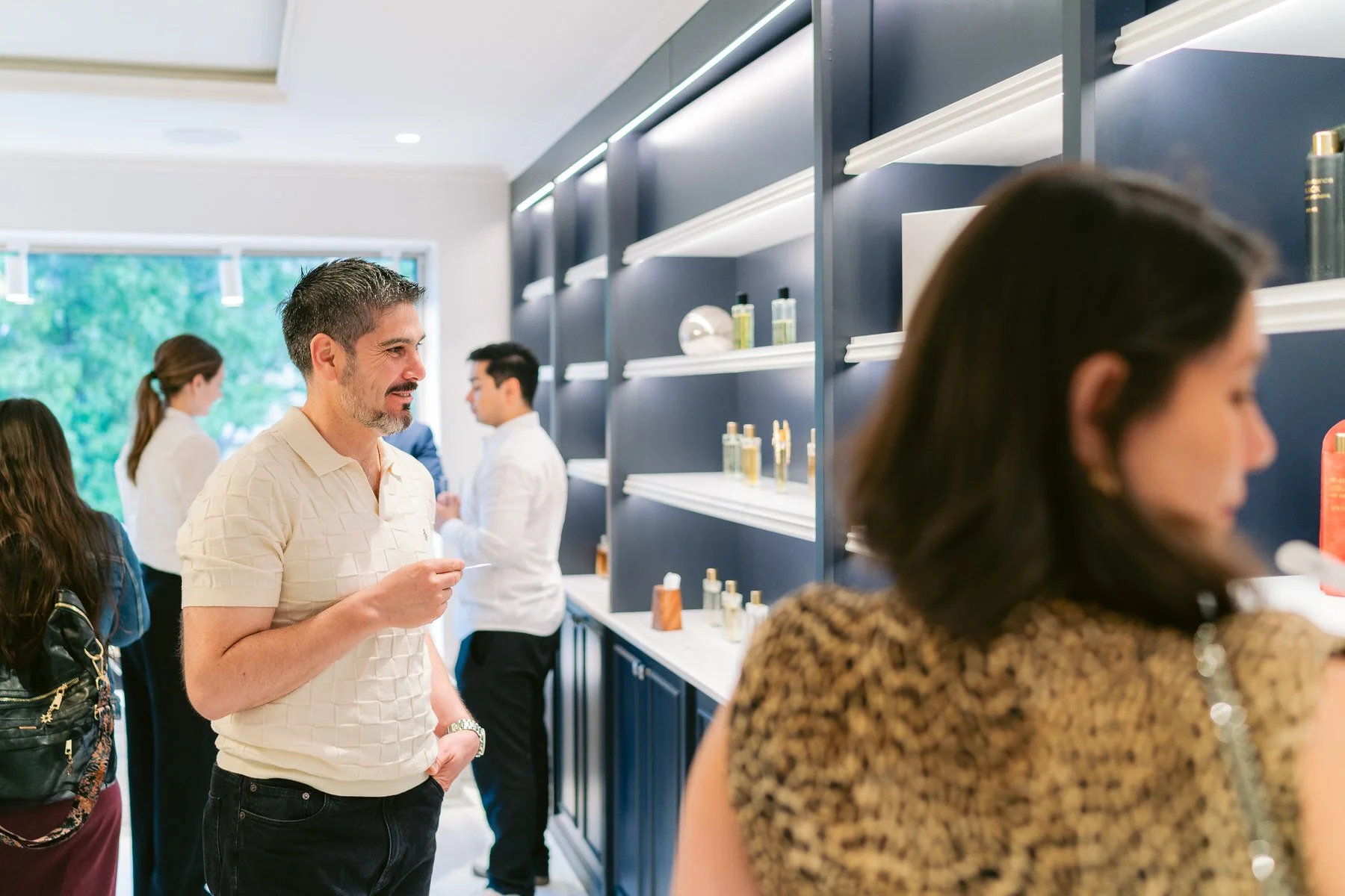 Varias personas en una tienda, una mujer con blusa de leopardo y otras personas en el fondo, en la estética moderna de una tienda o galería