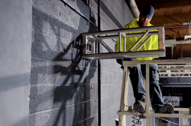 A man in work clothes, working on The Story Factory trusses