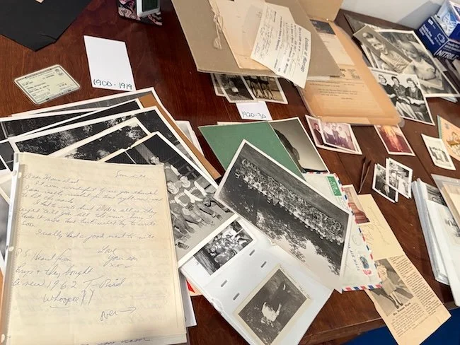table with many old photos and newspaper clippings, letters