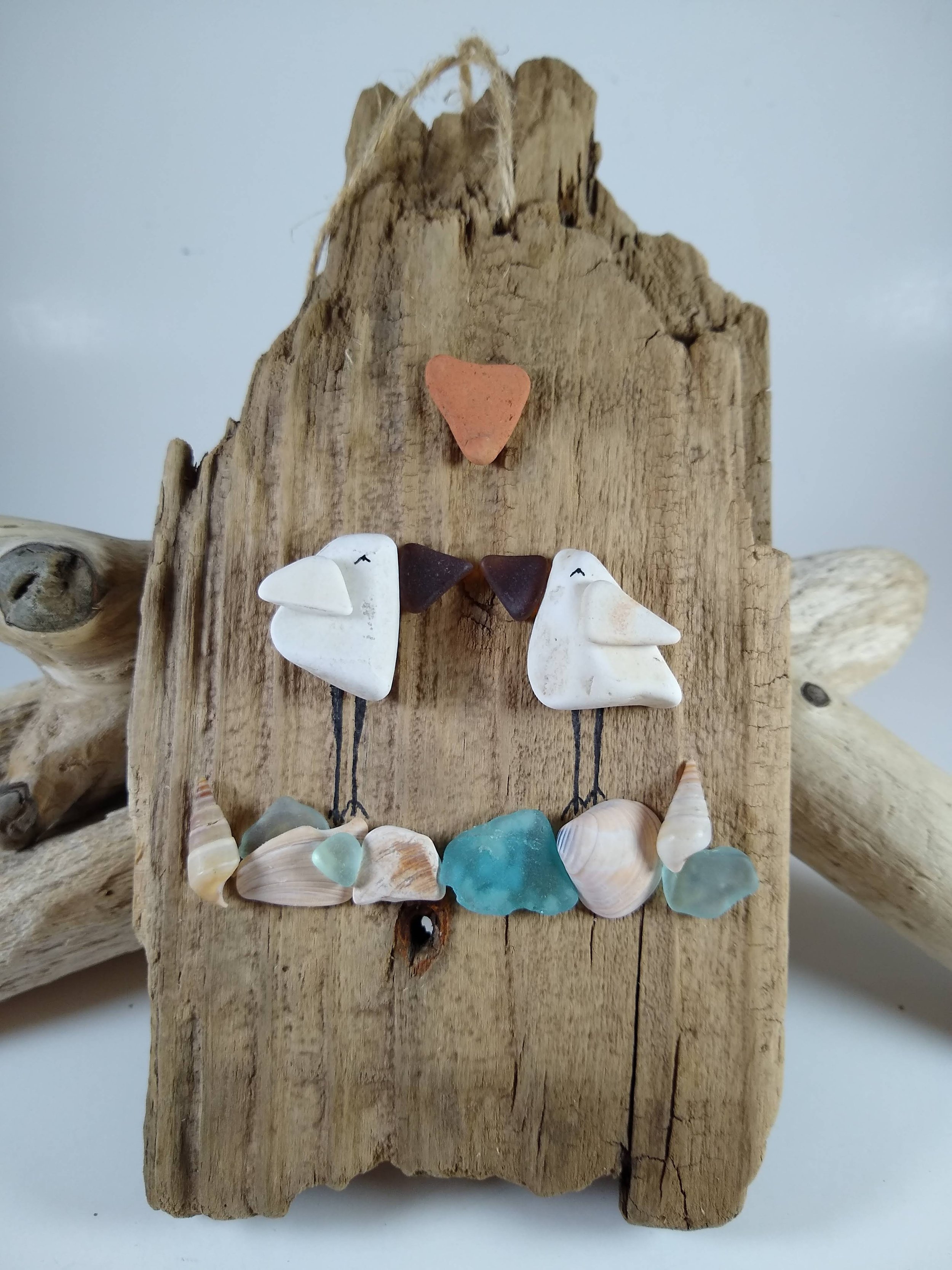 This old weathered board is a beautiful backdrop to these beach pottery love birds.