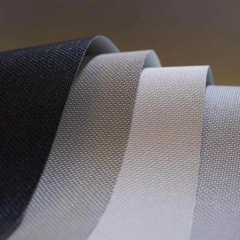 Four rolls of fabric in black, dark gray, light gray, and silver, arranged in a row.