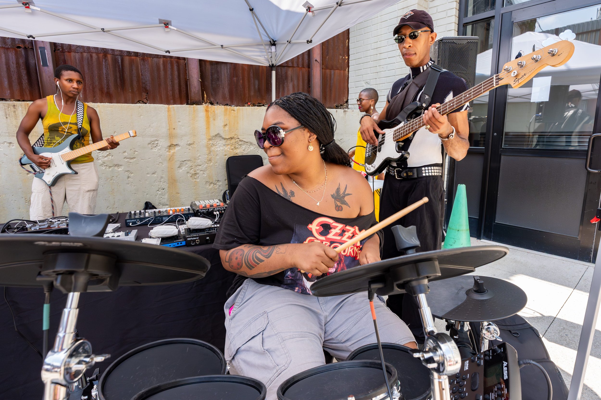 A woman playing the drums with a band behind her