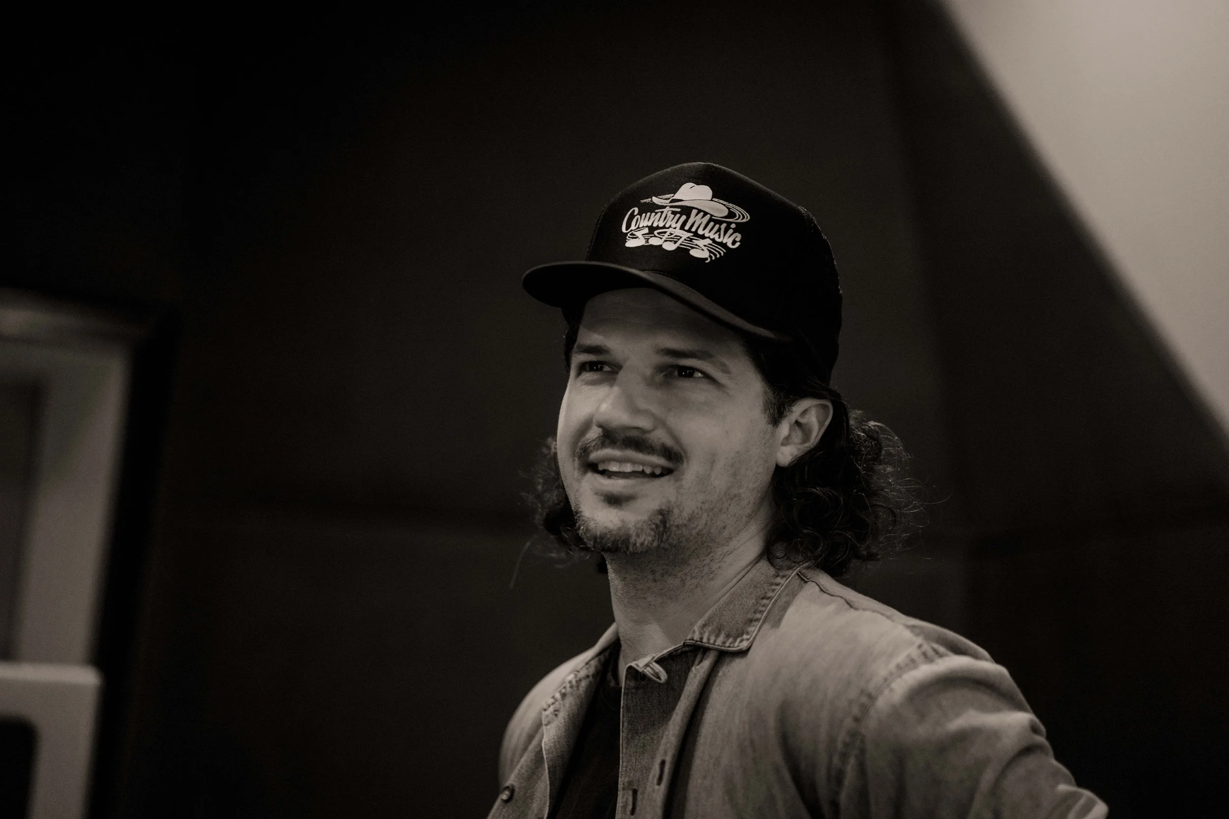 Black and white portrait of man smiling in a recording studio.