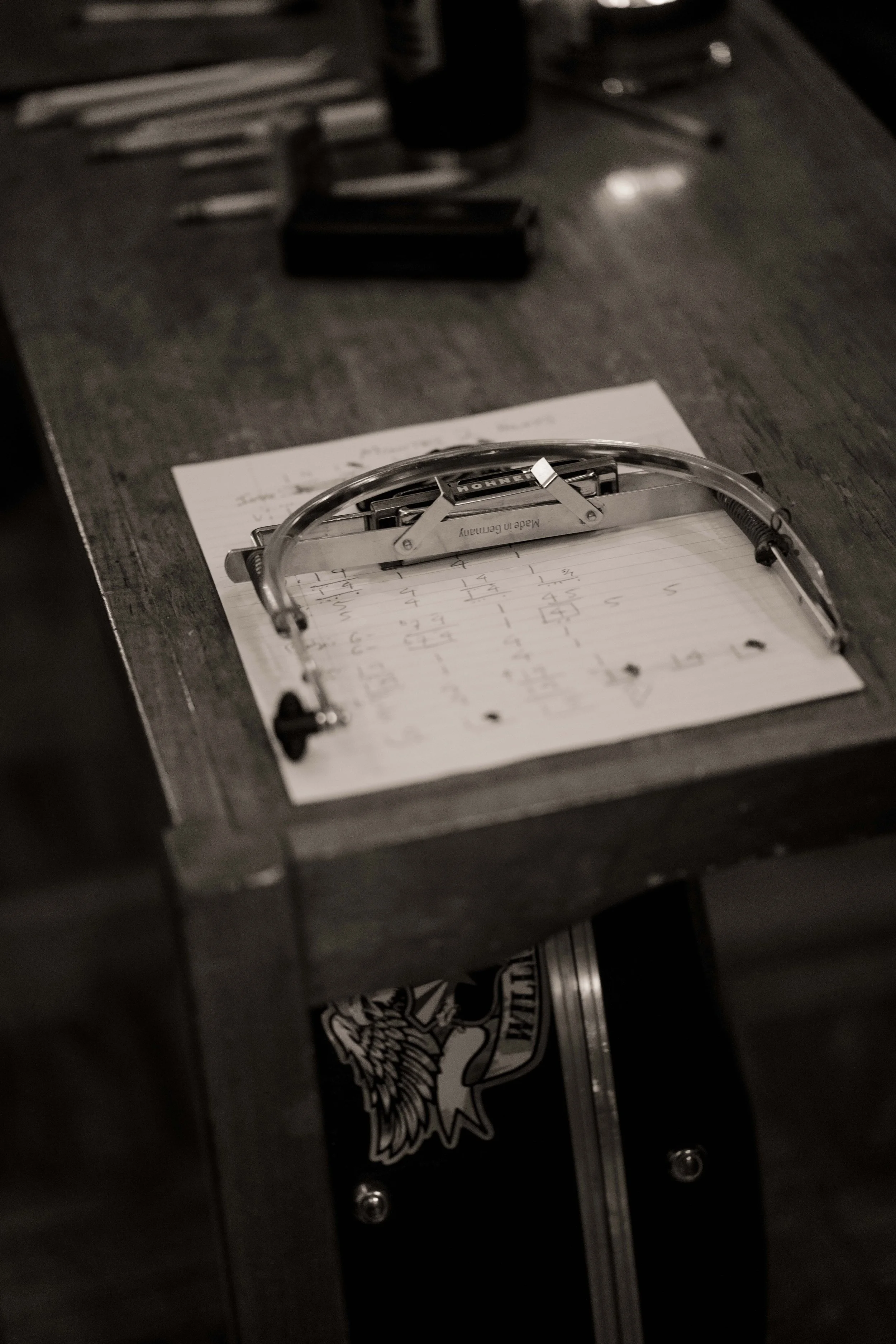 Harmonica sitting on top of handwritten music chords in a recording studio.