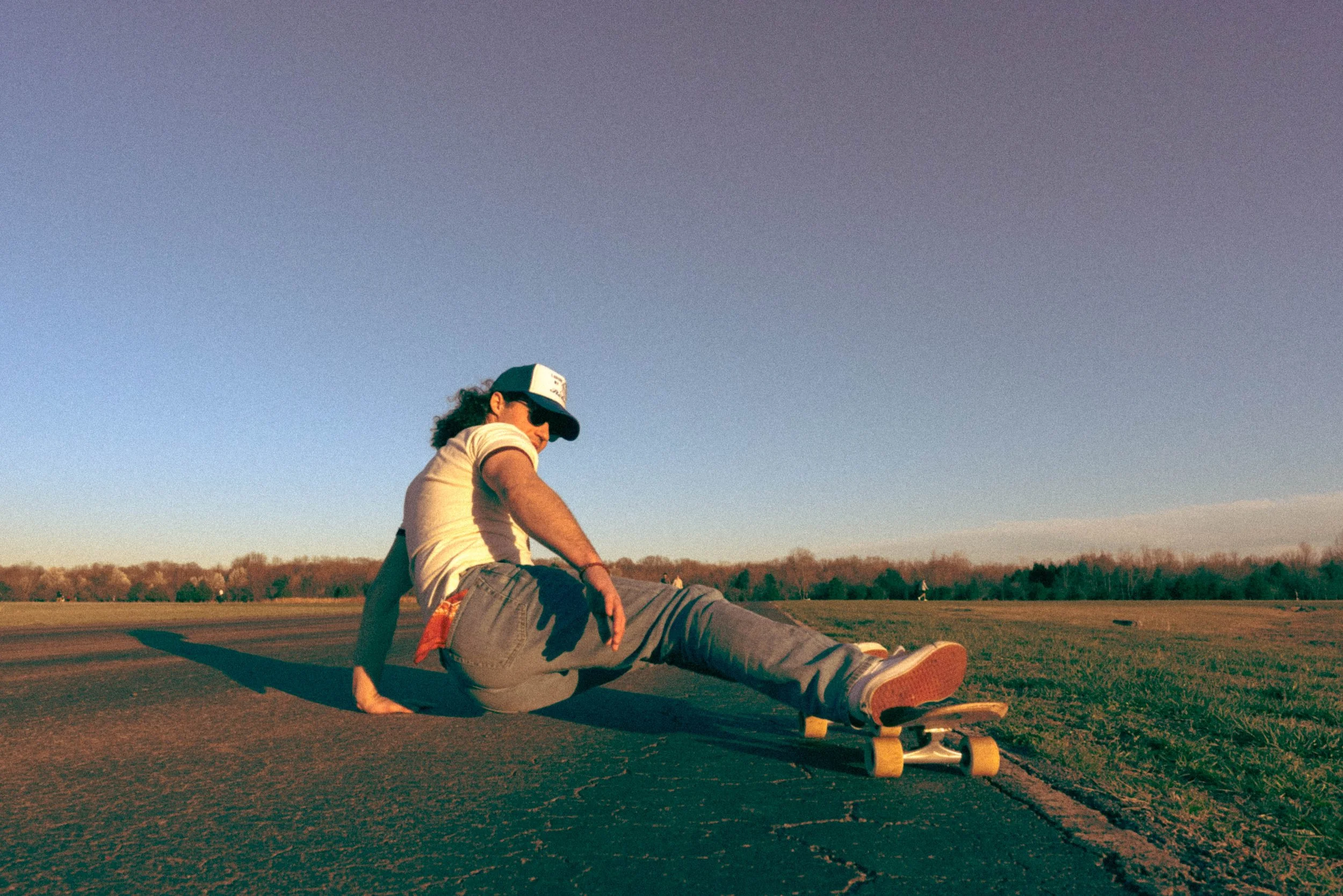 Vintage style full coverage image of a man with a skateboard. He is balancing on one hand with his feet up on the skateboard.